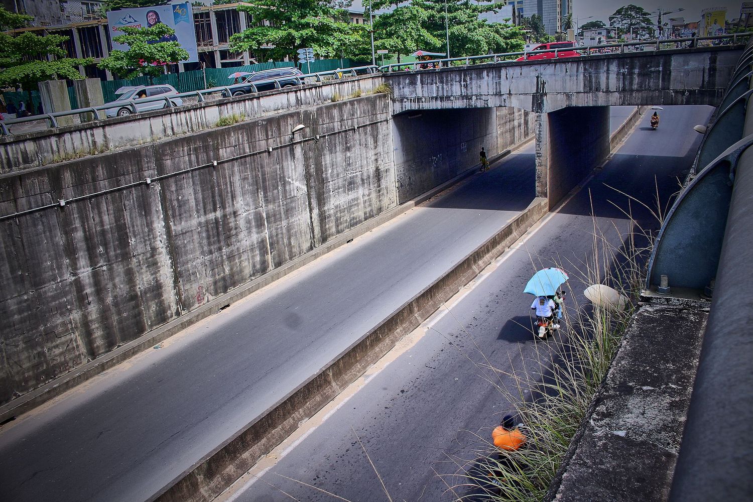 Aerial view of urban underpass tunnel with pedestrians carrying umbrella.