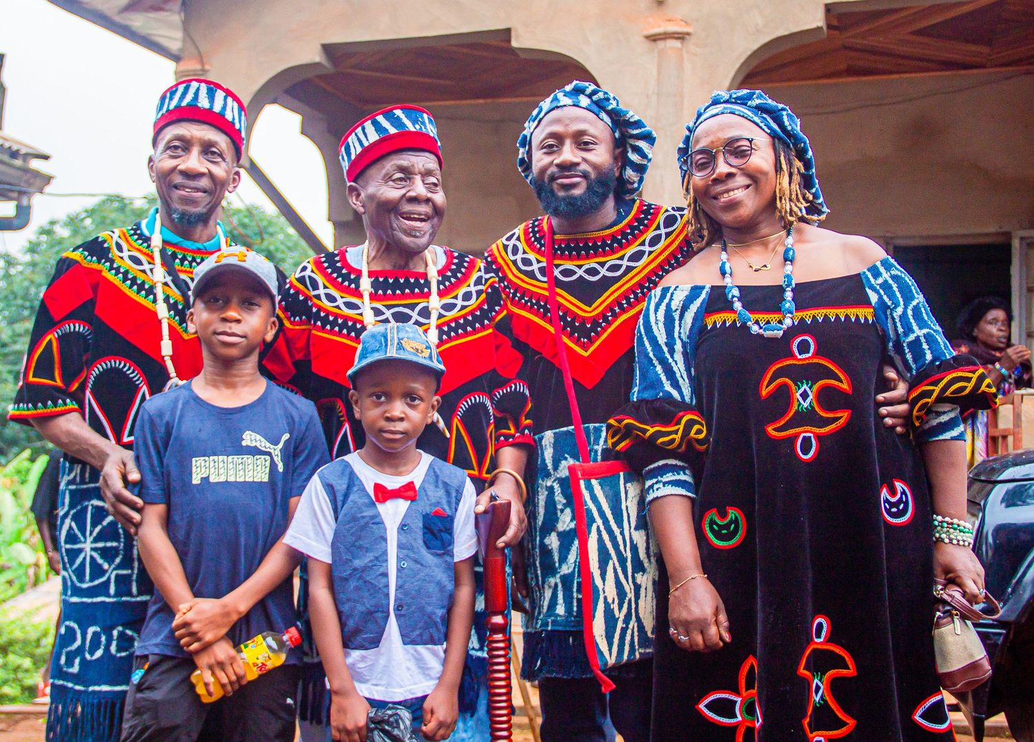 Family in vibrant traditional African attire posing together outdoors, celebrating cultural heritage with colorful patterns.