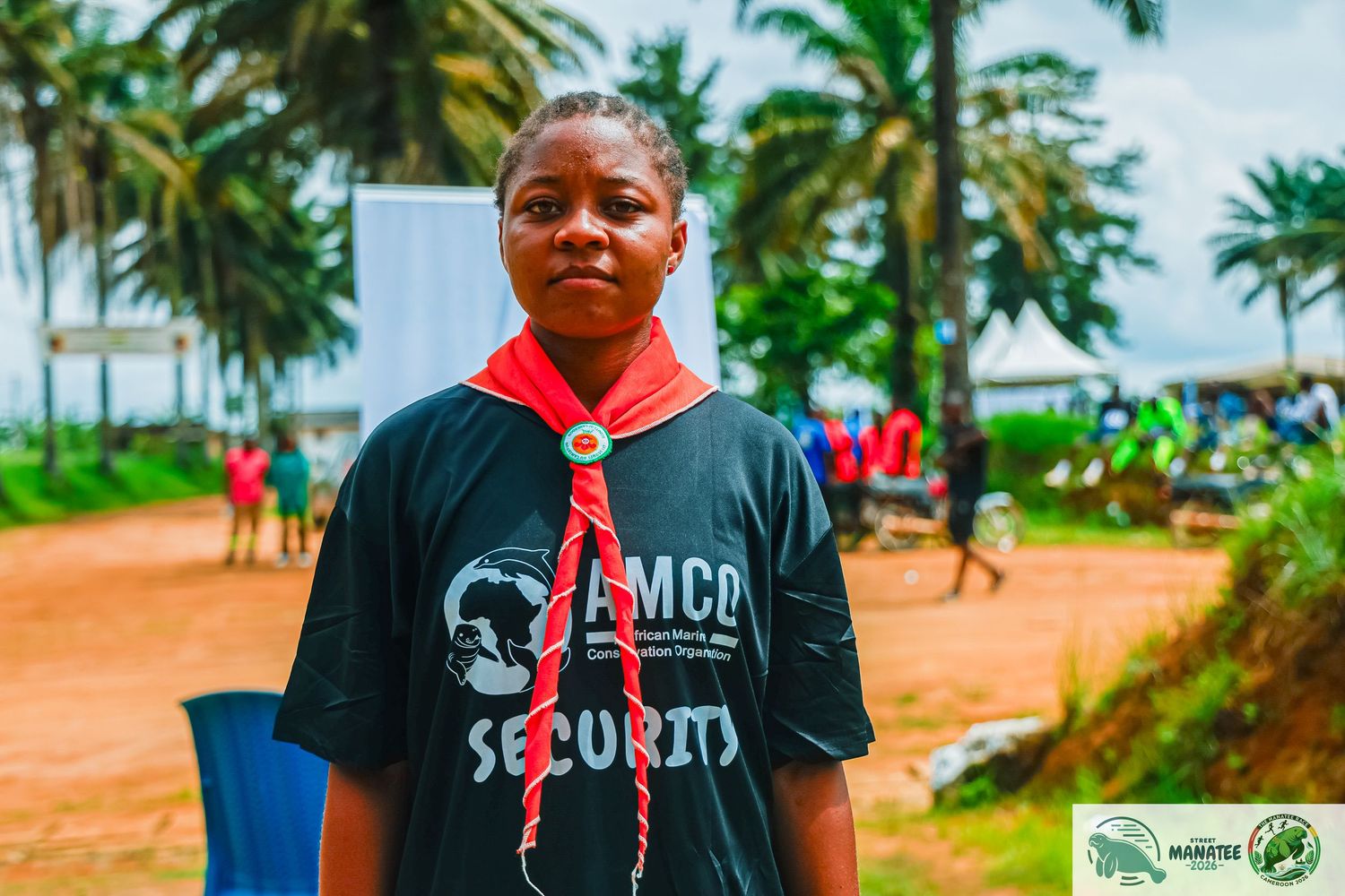 Young person in AMCO Security black t-shirt with red scarf outdoors.