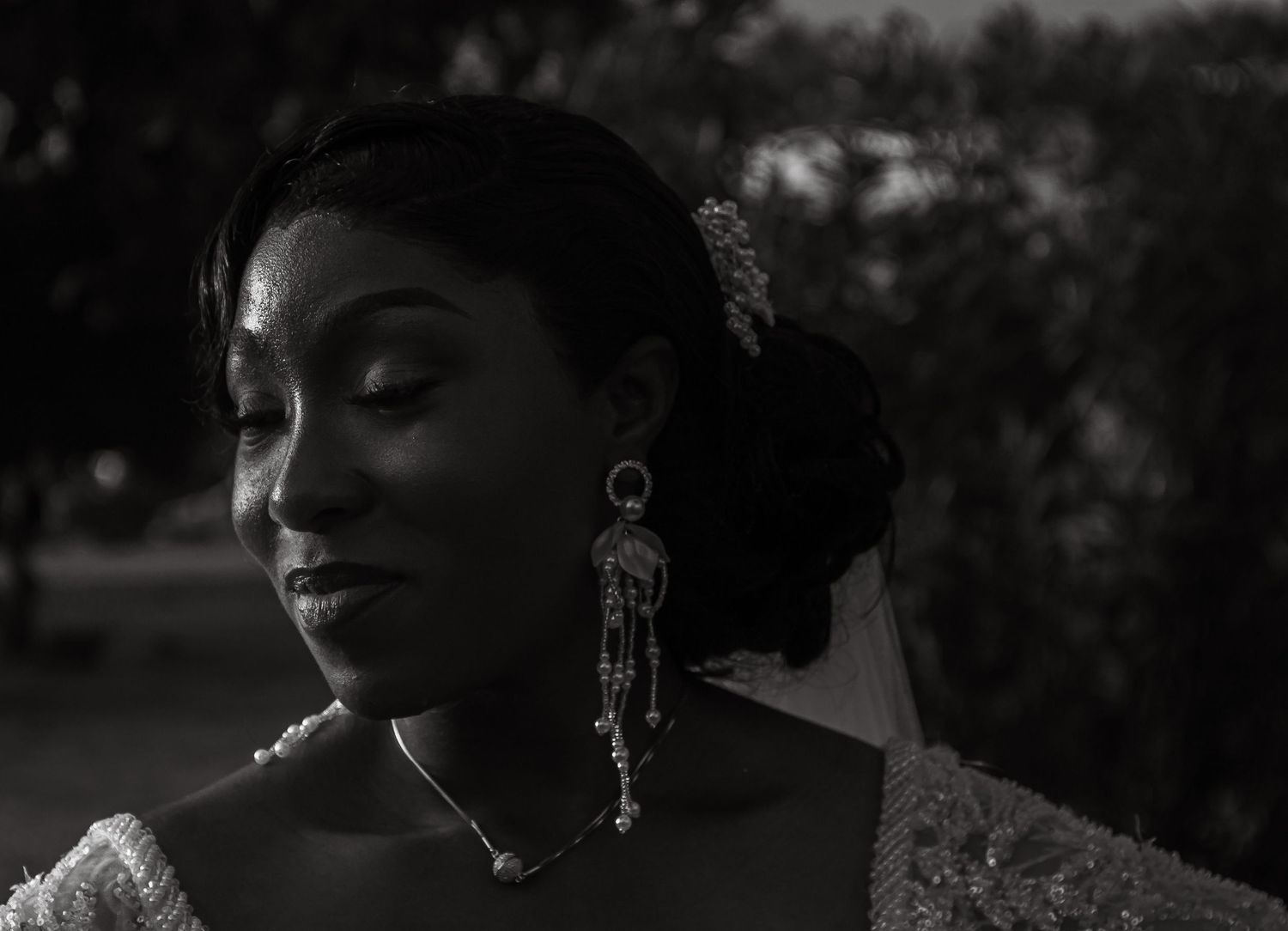 Elegant black and white portrait of an African bride with decorative earrings and hair accessory.
