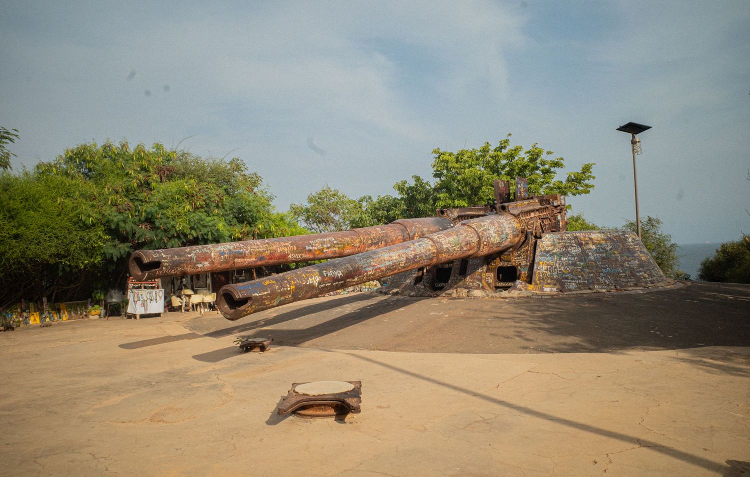 Large rusty historic cannon displayed outdoors at a coastal fort in West Africa.