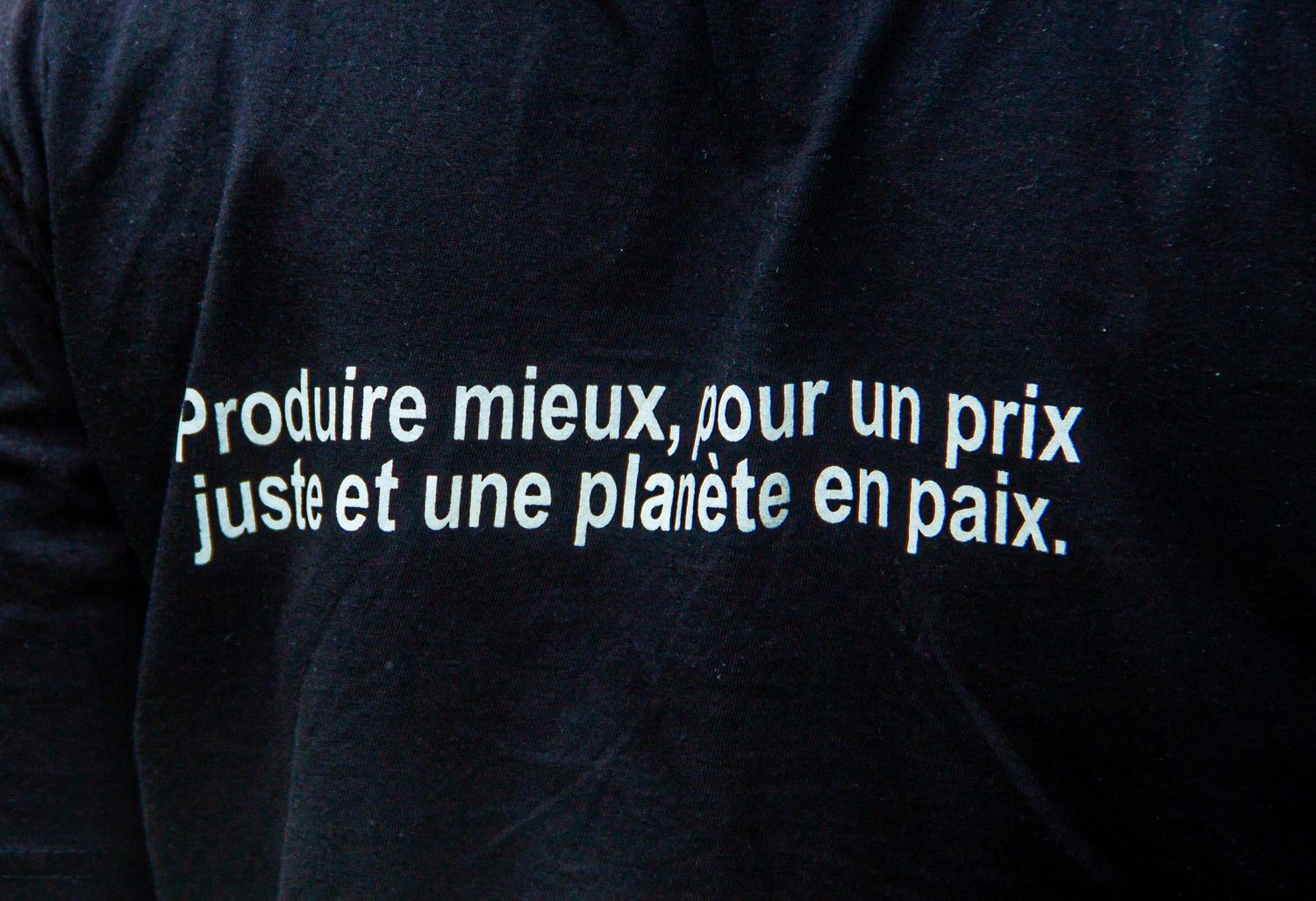 Close-up of a black t-shirt with French text reading Produire mieux, pour un prix juste et une planete en paix.