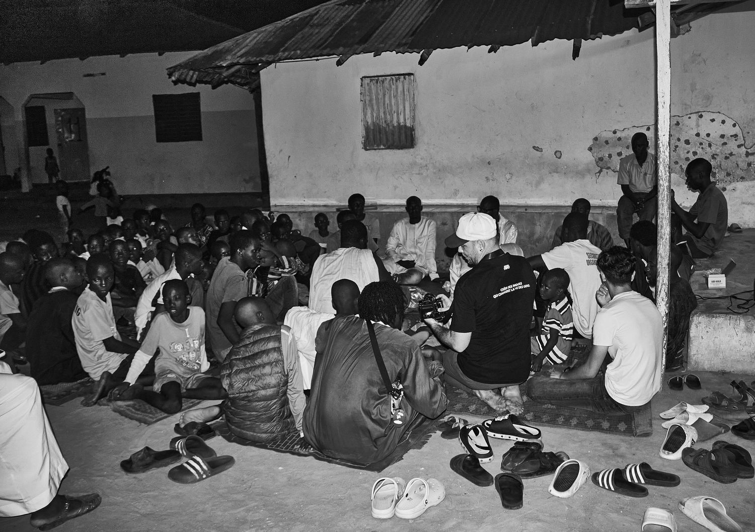 Large group of people sitting on the floor inside a community gathering hall.