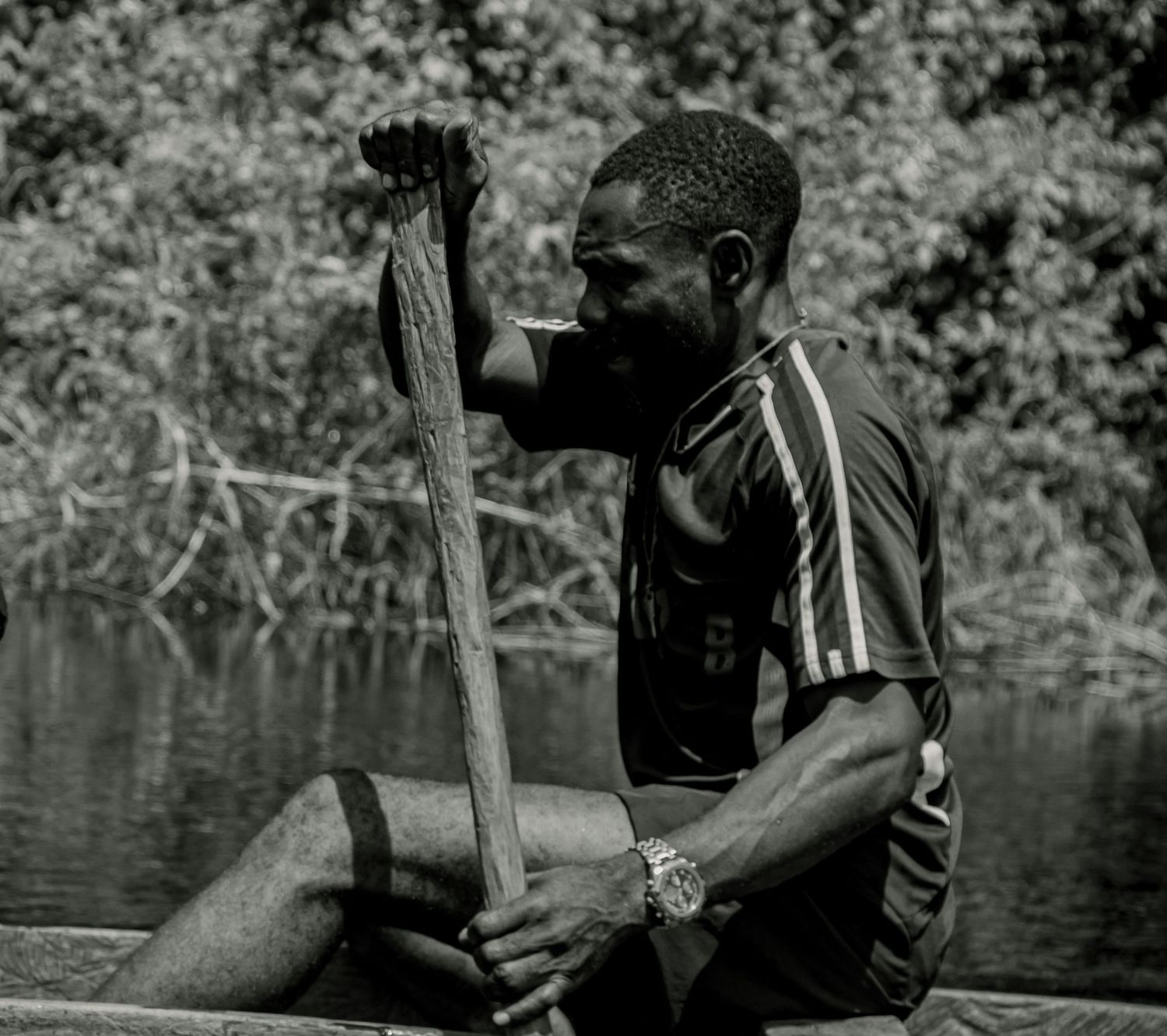 Black and white photo of man rowing a boat on a calm river.