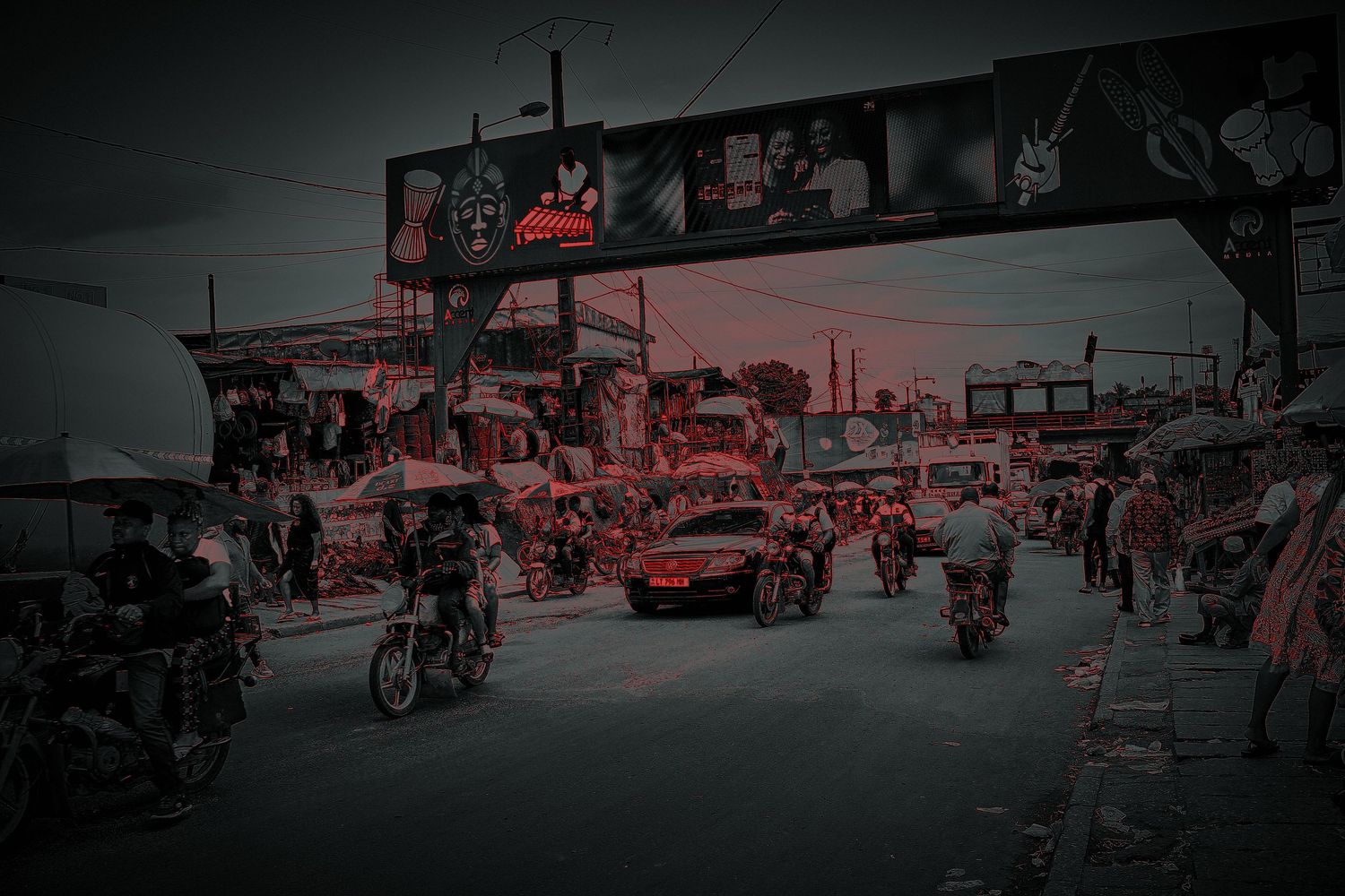 Busy urban street market with motorcycles and cars at dusk in a West African city.