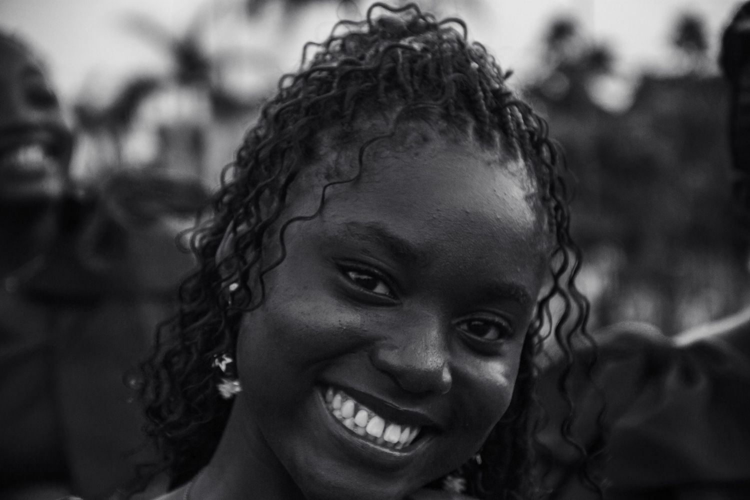 Smiling young woman with curly hair in black and white portrait outdoors.