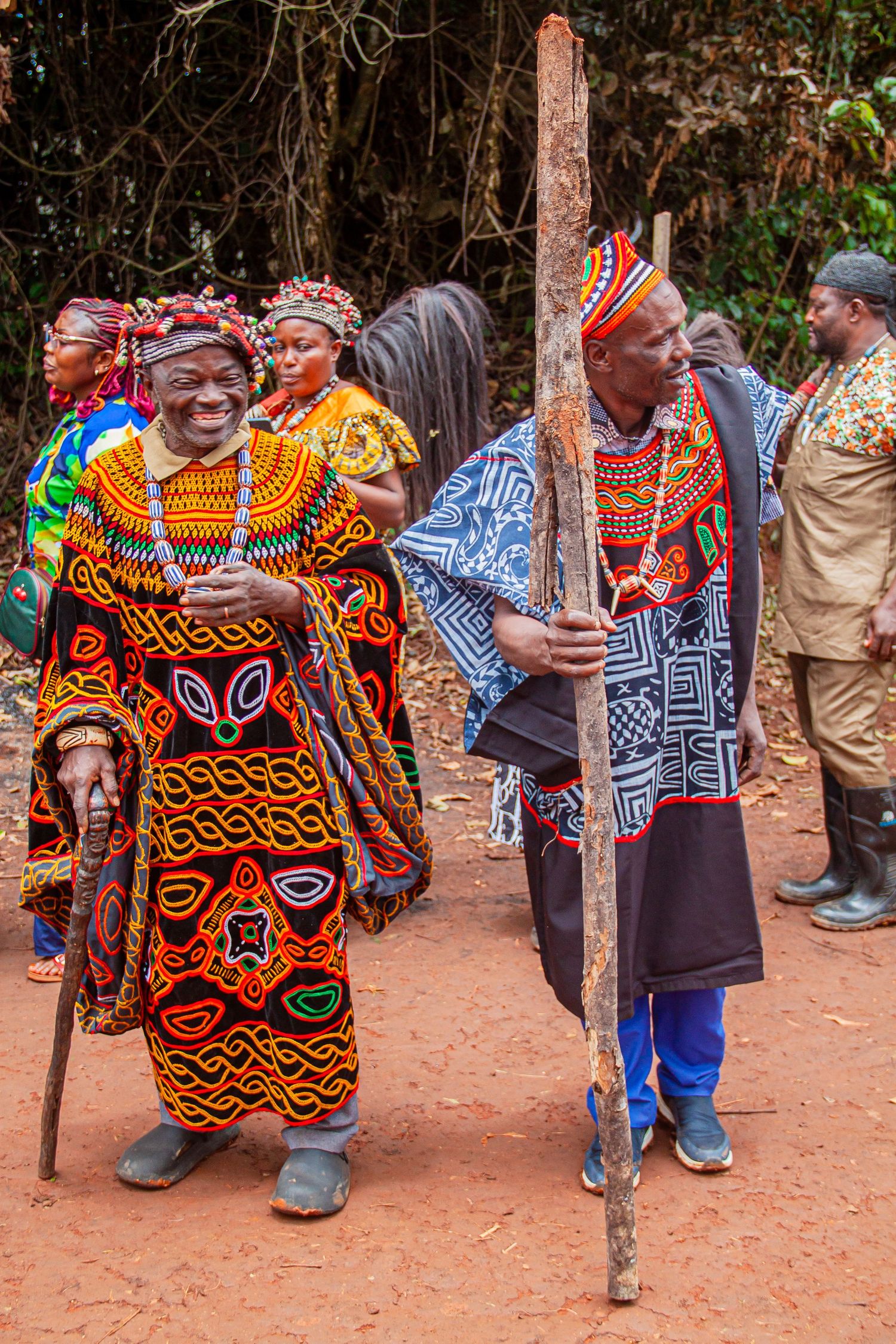 Two elderly African men in vibrant traditional Cameroonian attire smiling during a cultural celebration.