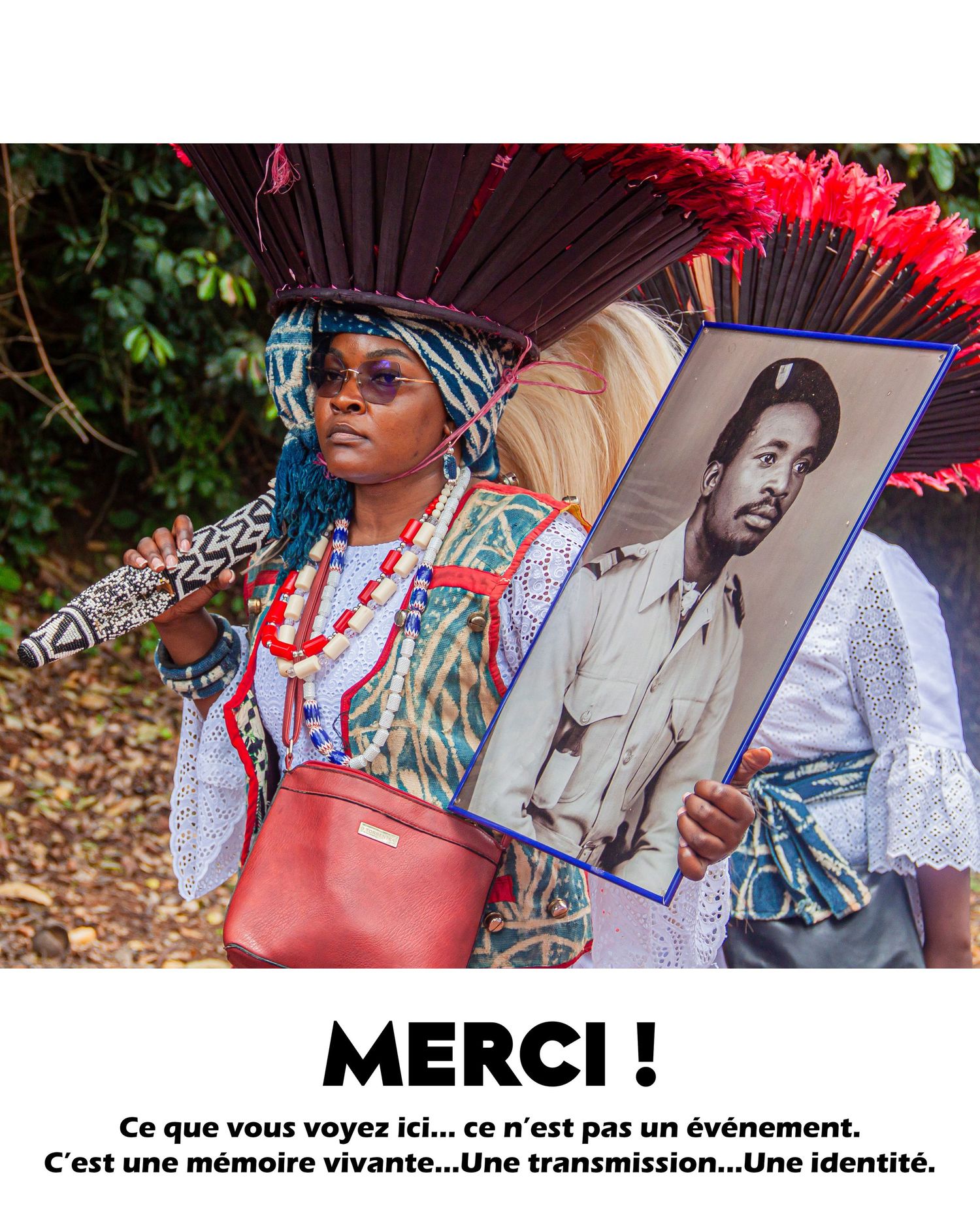 Woman in colorful traditional attire holds a portrait photo at a cultural memory and identity transmission ceremony outdoors.