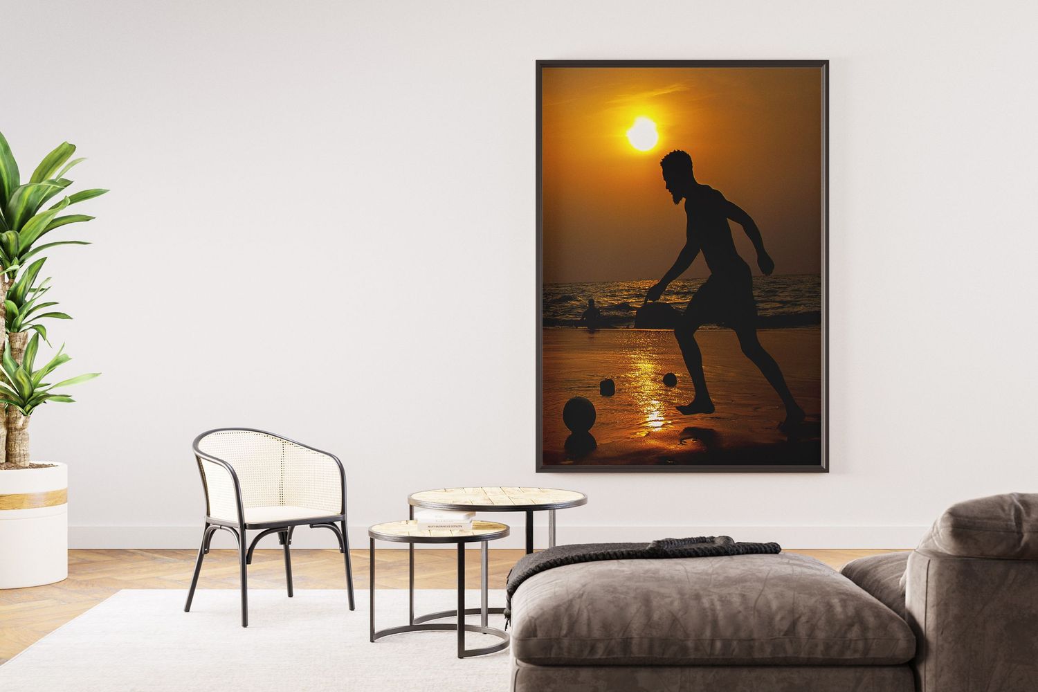 Framed sunset silhouette photo of a person playing soccer on a beach hanging on a white wall.