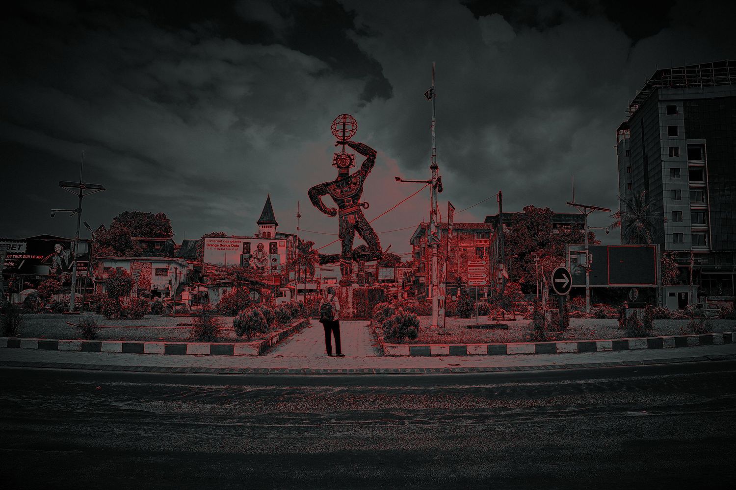 Dark moody photo of a warrior statue at a roundabout in an African city.