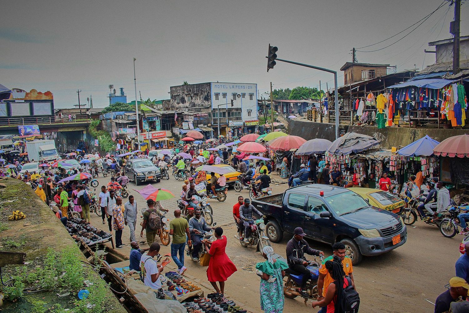 Busy African street market with colorful umbrellas, motorcycles and crowd.