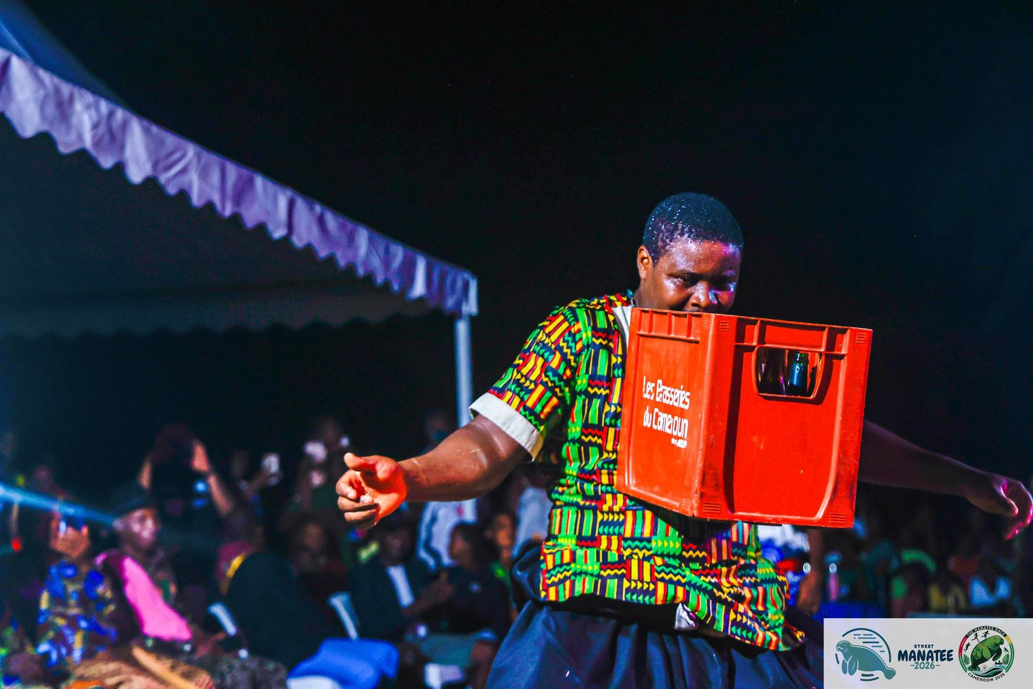 Man carrying red cooler box at vibrant nighttime cultural celebration event.