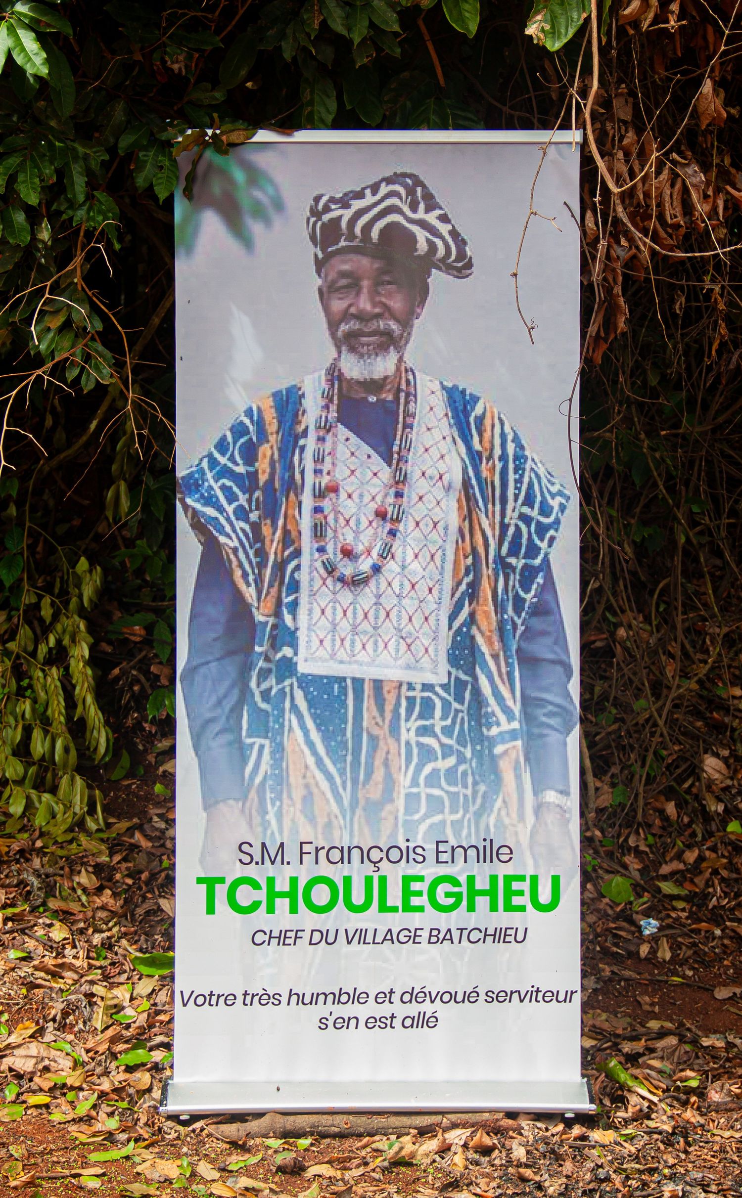 Memorial banner for S.M. François Emile Tchoulegheu, Chef du Village Batchieu, showing elder in traditional African attire.