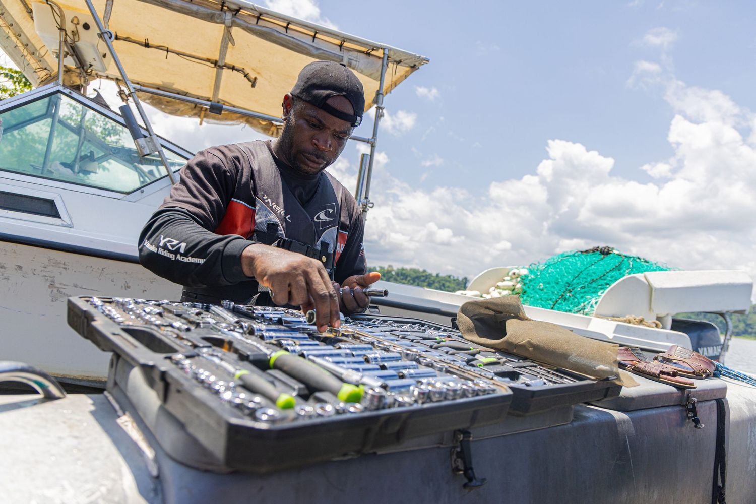 Field researcher organizes scientific equipment and tools in a tackle box on a research boat.