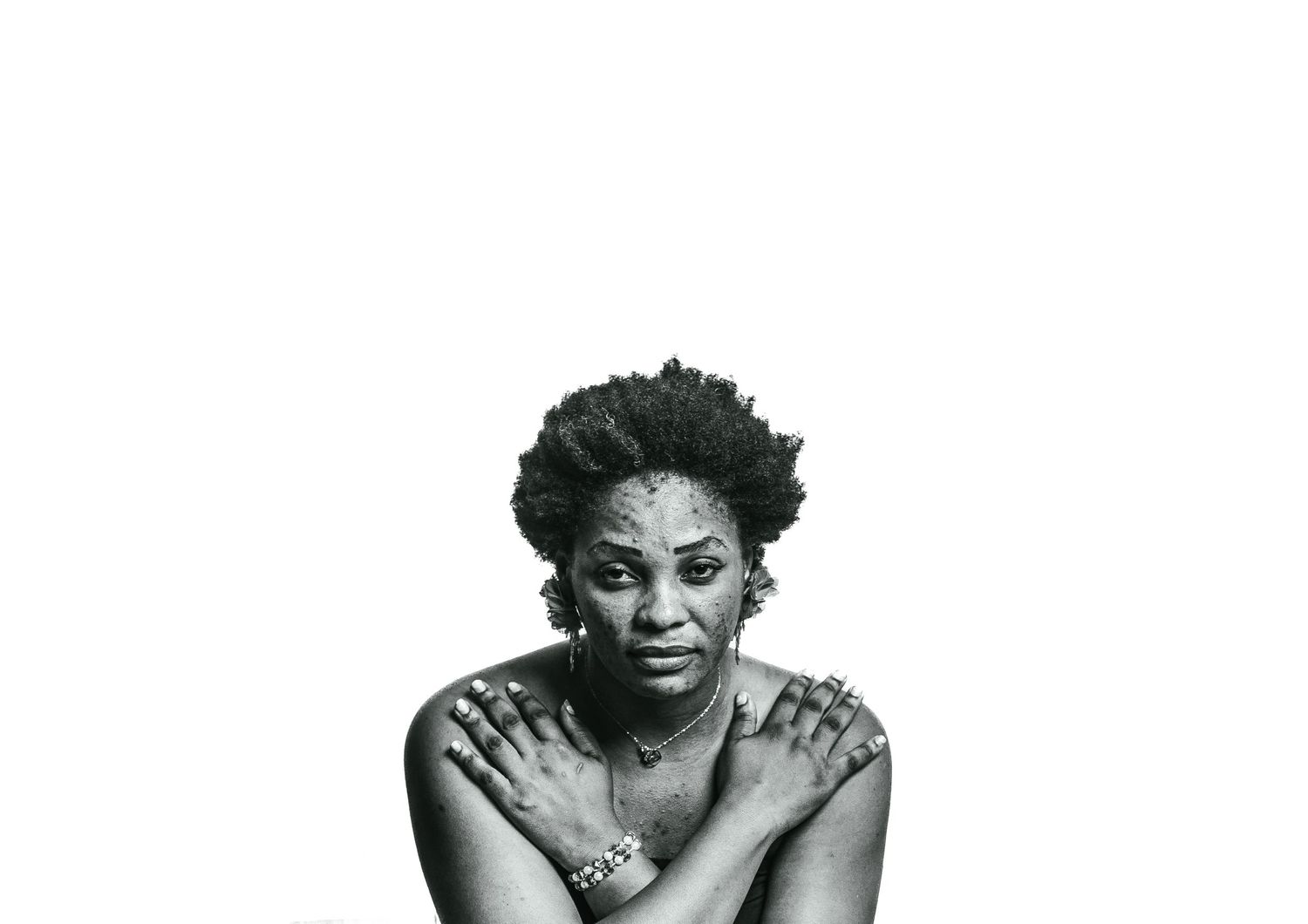 Black and white portrait of African woman with arms crossed against white background.