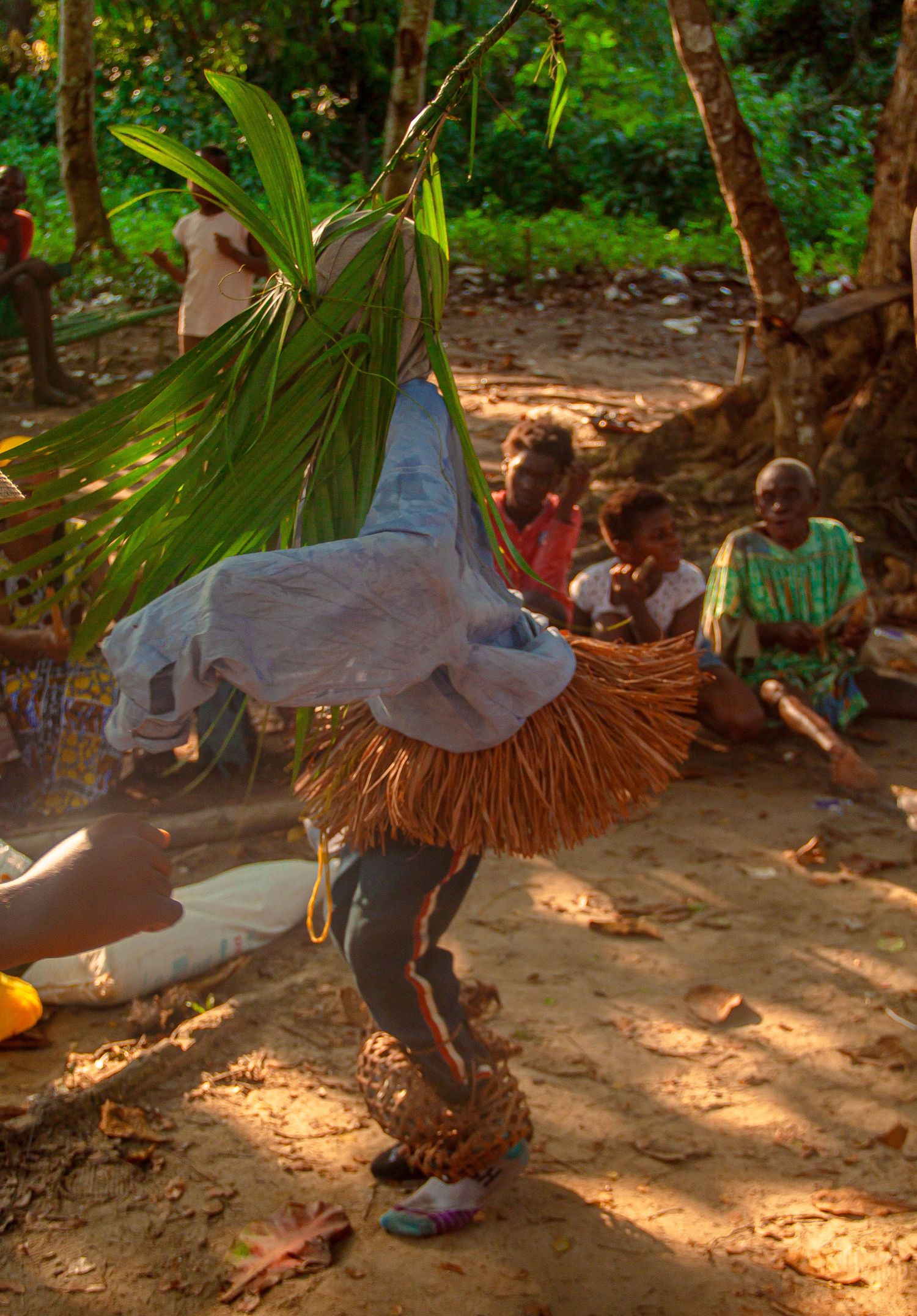 Traditional African masked dancer performing ritual dance for village community outdoors.