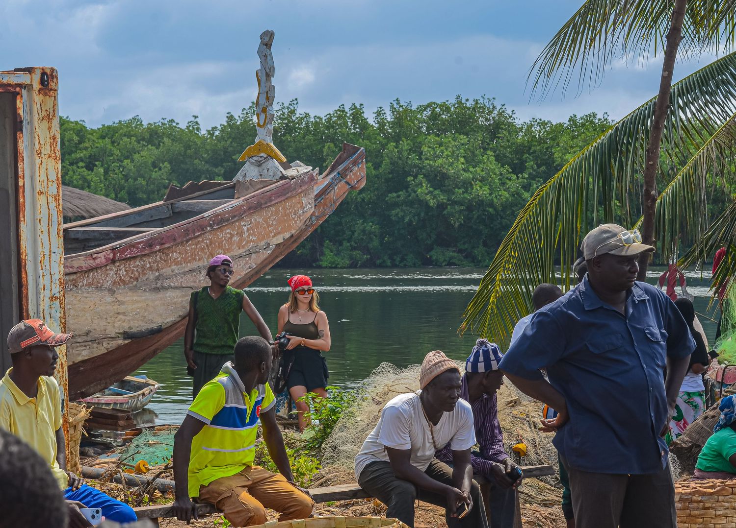 Group of fishermen working with nets and boats on tropical riverbank with mangroves.