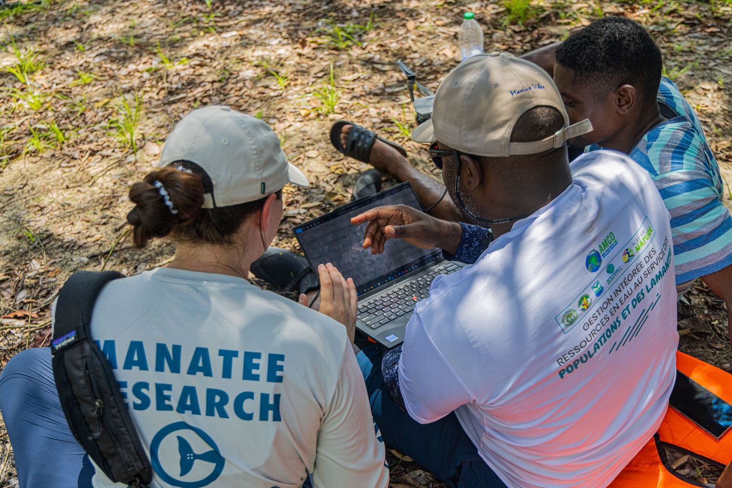 Manatee research team members review data on a laptop computer during an outdoor wildlife study.