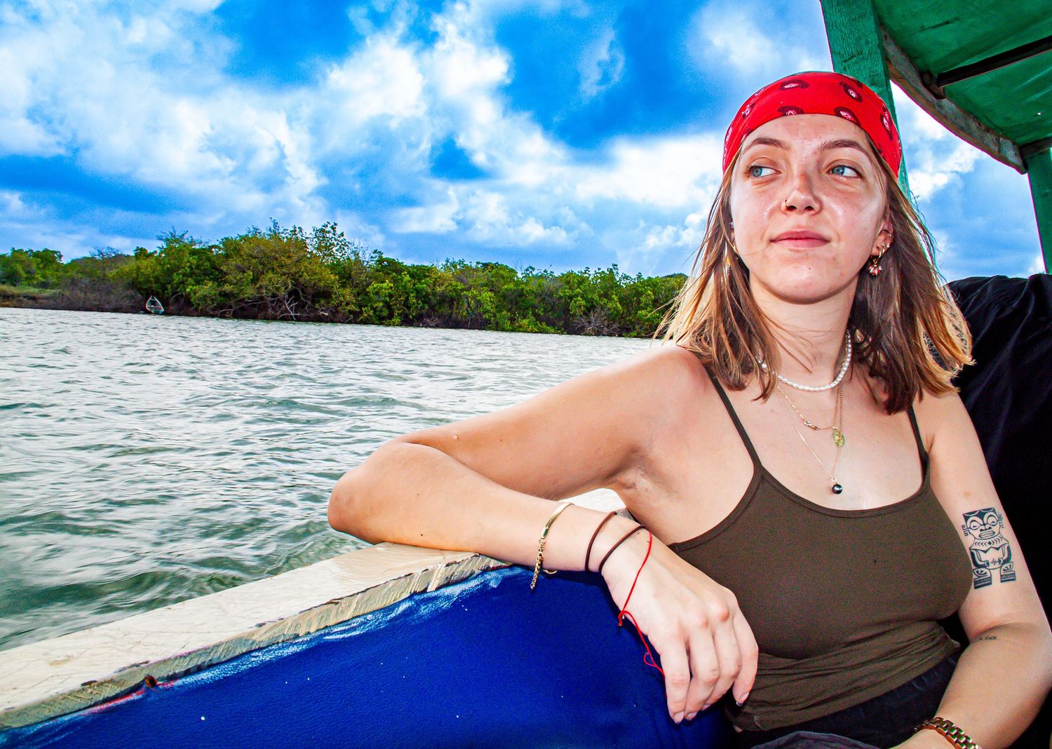 Young woman in red bandana relaxing on a wooden boat on a tropical river.