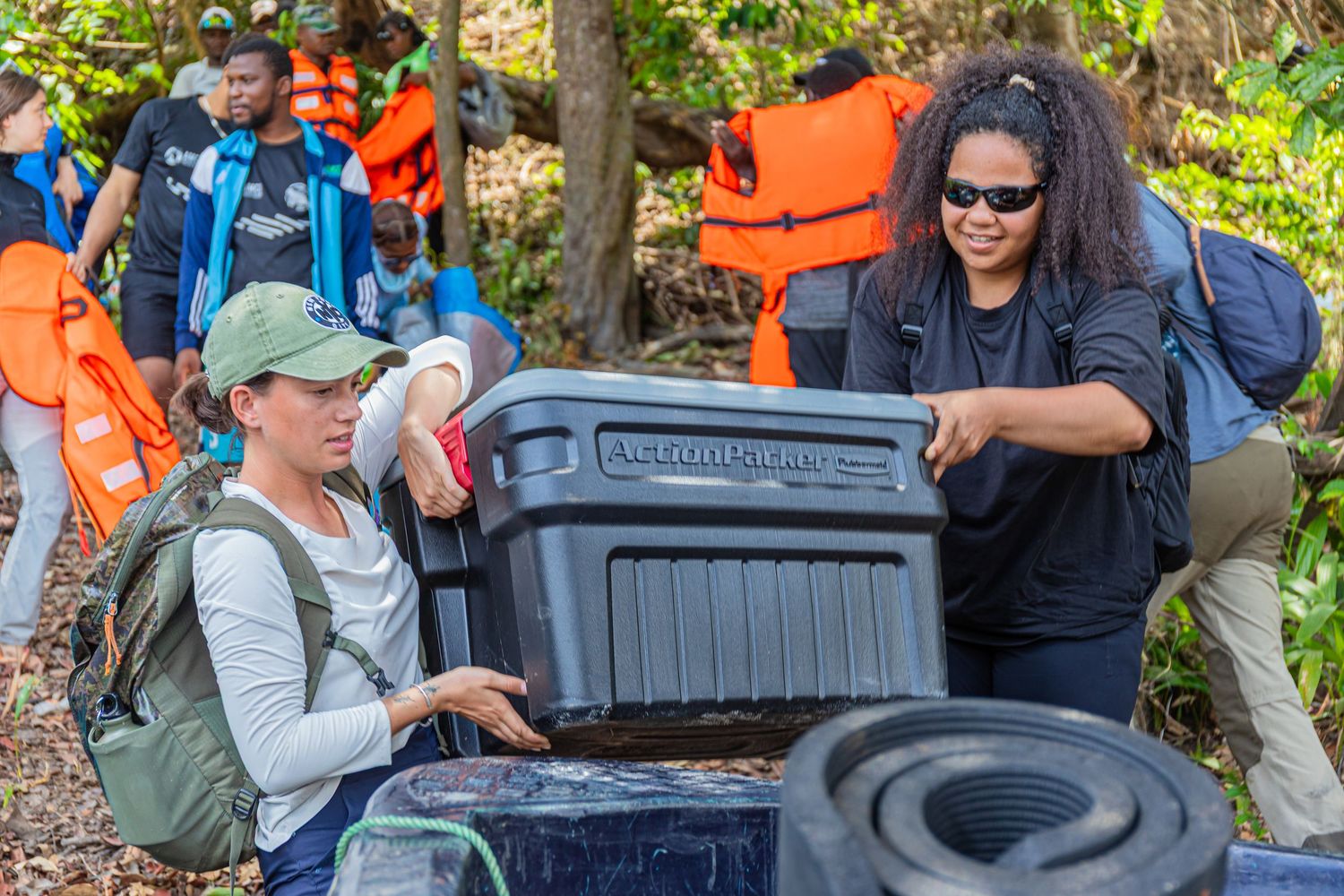 Two researchers open a large waterproof equipment case during a manatee conservation fieldwork expedition.