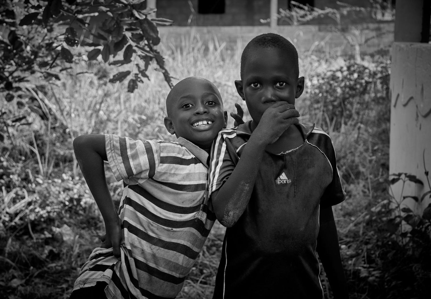 Two African boys posing together outdoors in black and white portrait photography.