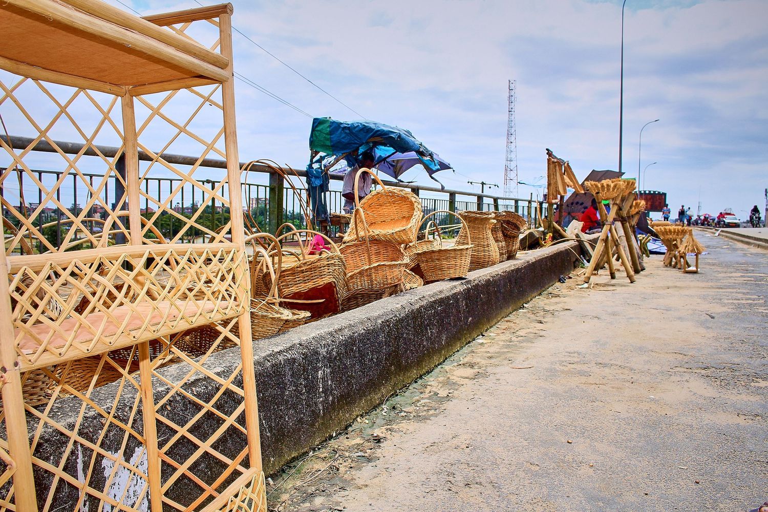 Handmade wicker baskets and rattan furniture displayed for sale along a sunny roadside market.