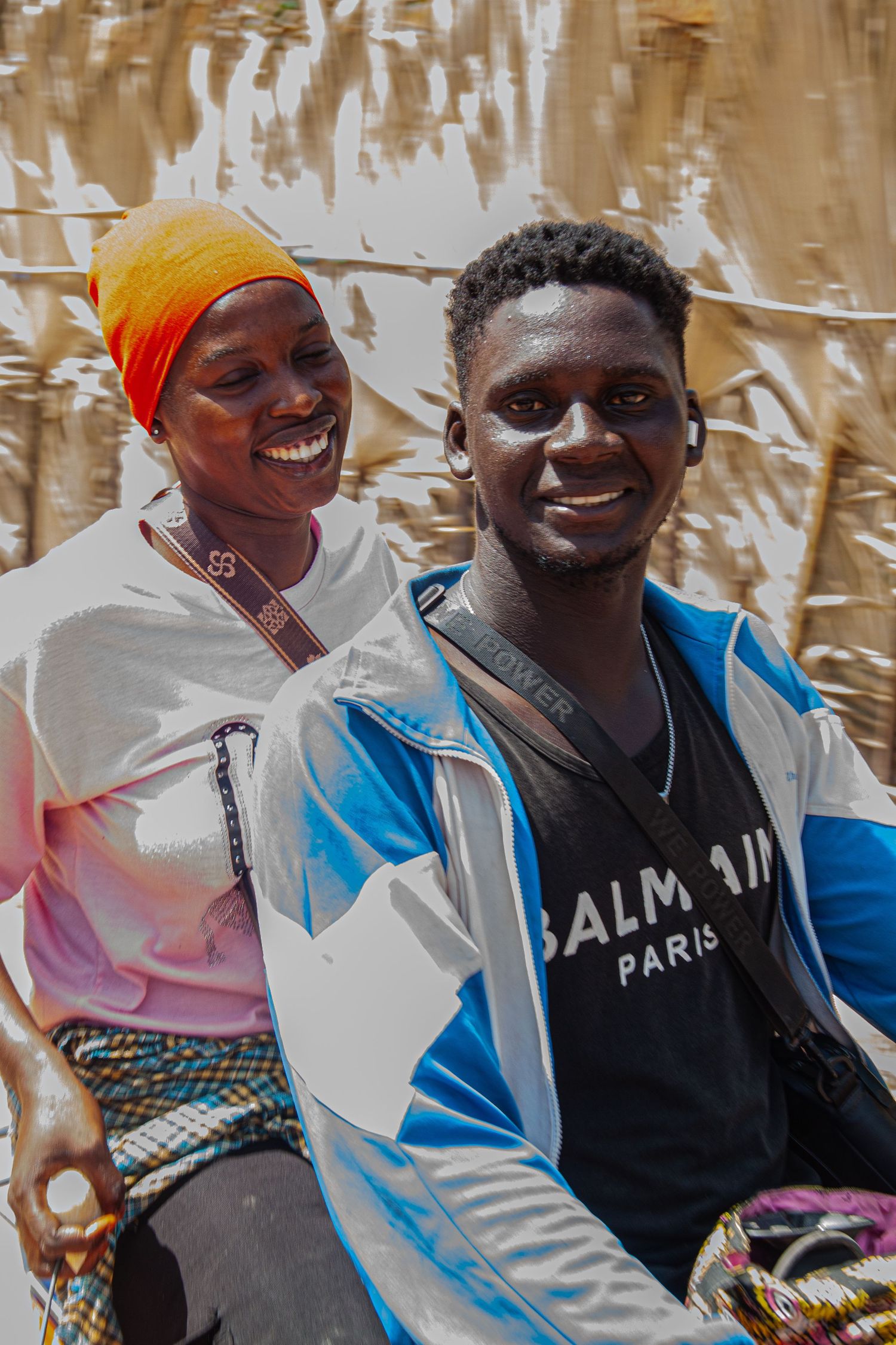 Happy Senegalese couple smiling together outdoors, man wearing a Balmain Paris jacket.