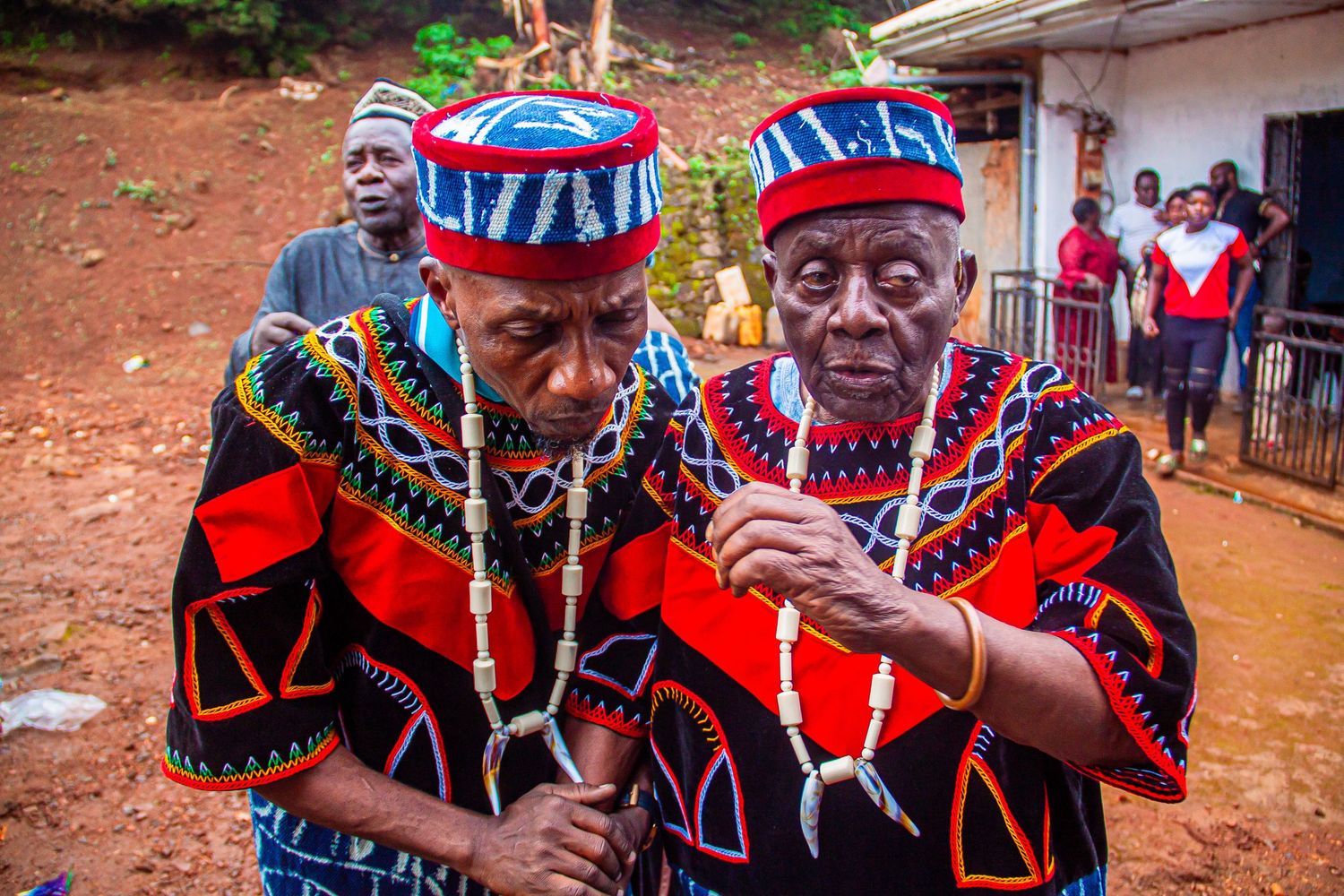 Two elderly African men in traditional Cameroonian royal attire conversing during a cultural ceremony.