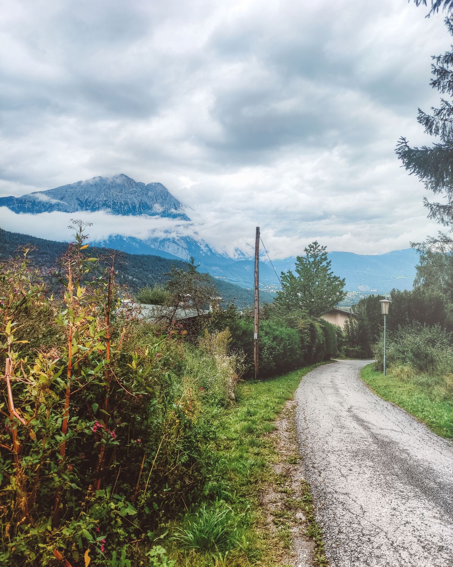 Winding rural mountain road heading towards a foggy alpine peak in Rietz Tirol Austria travel landscape photography art print.