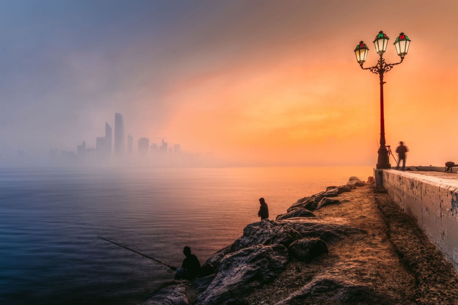 Heavy morning mist and orange sunrise over stone coastal pathway street lamps Abu Dhabi Corniche UAE landscape photography print.