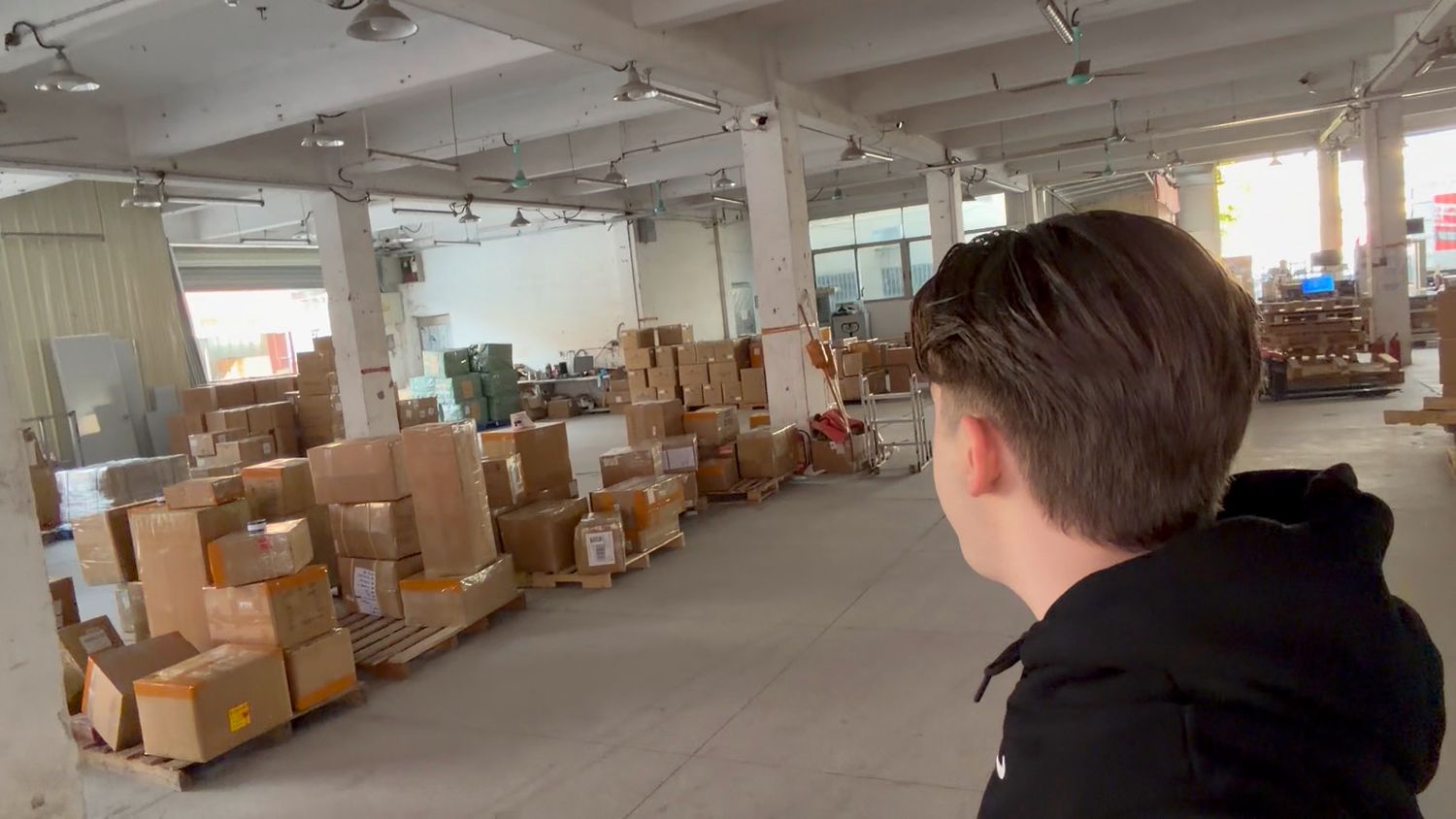Person overlooking a large warehouse filled with stacked boxes and goods.