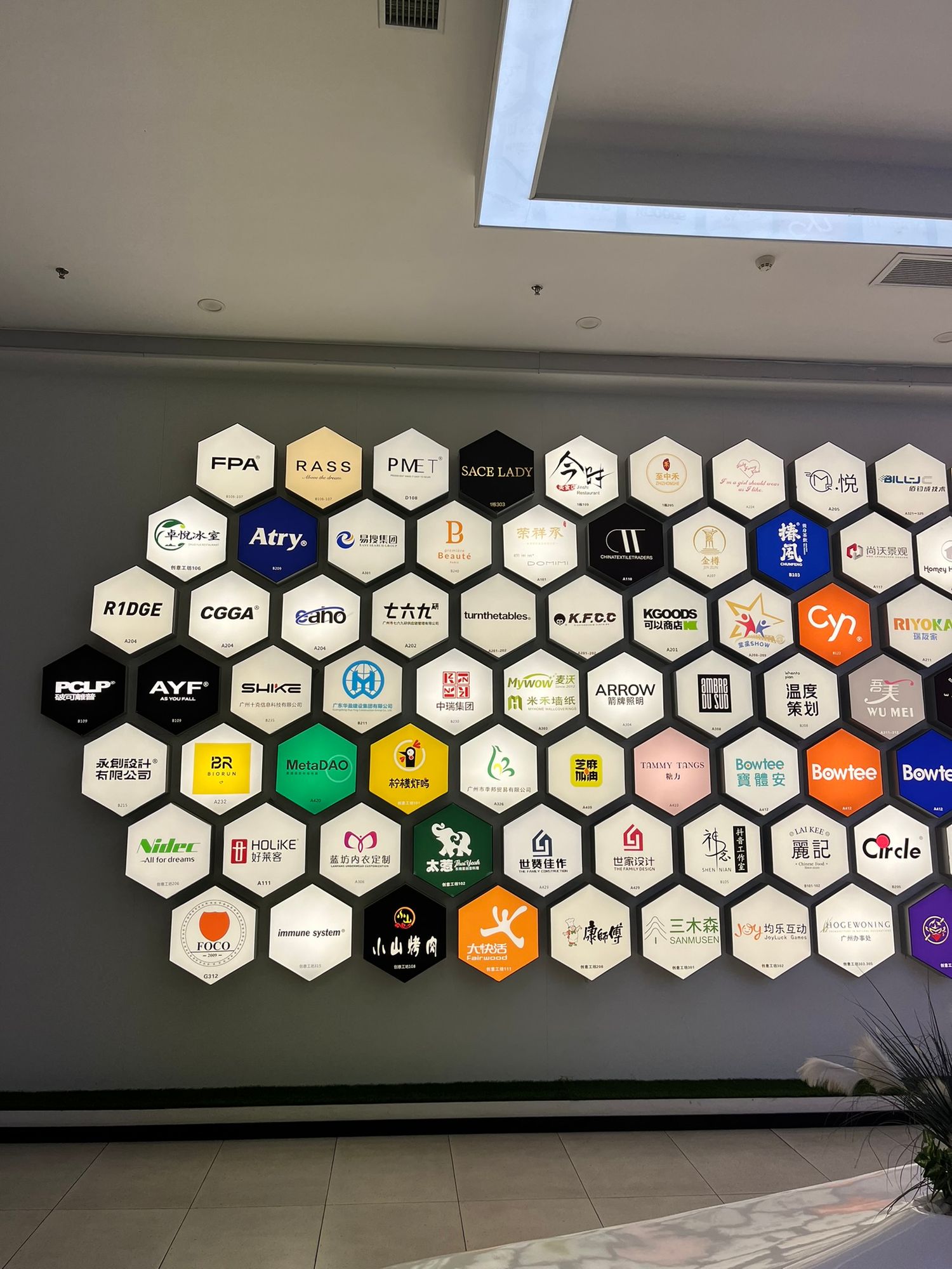 Colorful hexagonal brand logo wall display featuring multiple company logos in a modern office lobby.