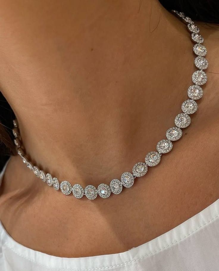 Elegant diamond halo tennis necklace in silver, featuring round brilliant-cut stones, worn on a woman's neckline.
