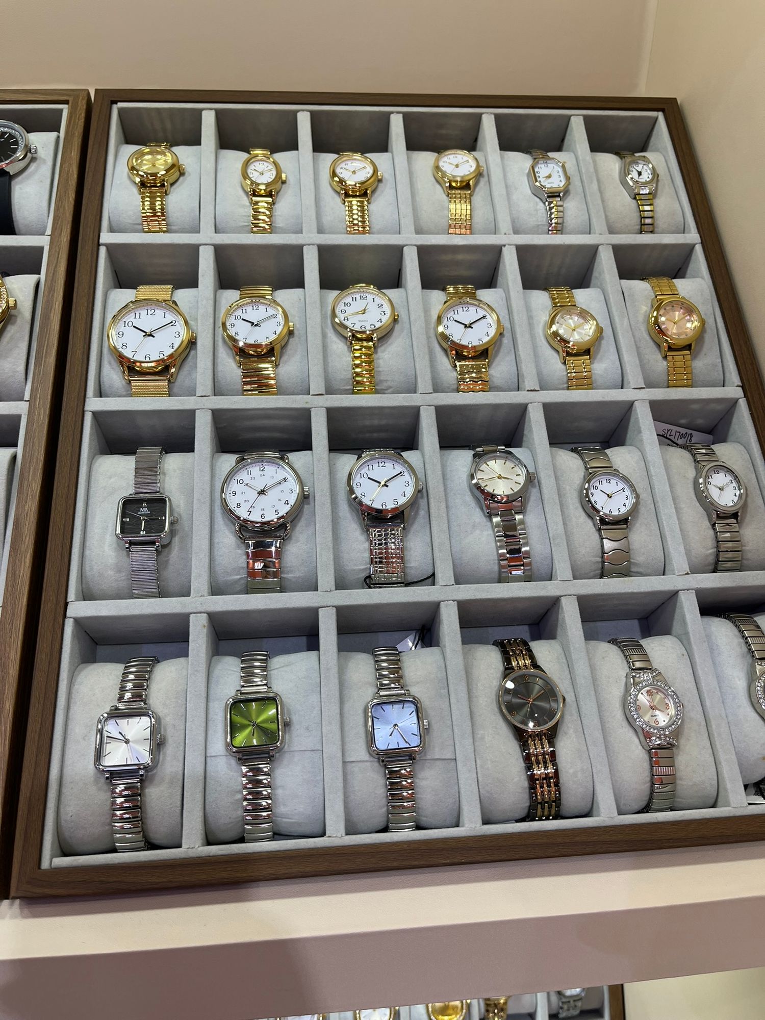 Display case showcasing a collection of elegant gold and silver women's wristwatches in a retail store.
