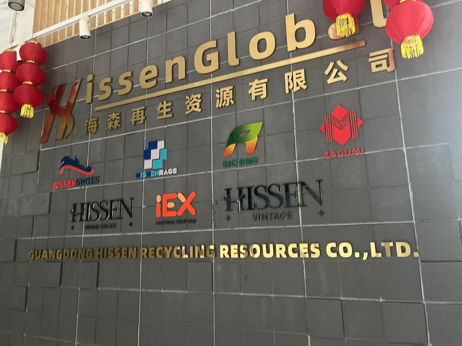 Hissen Global Guangdong Recycling Resources Co. Ltd. corporate signage on a dark wall with red lanterns.