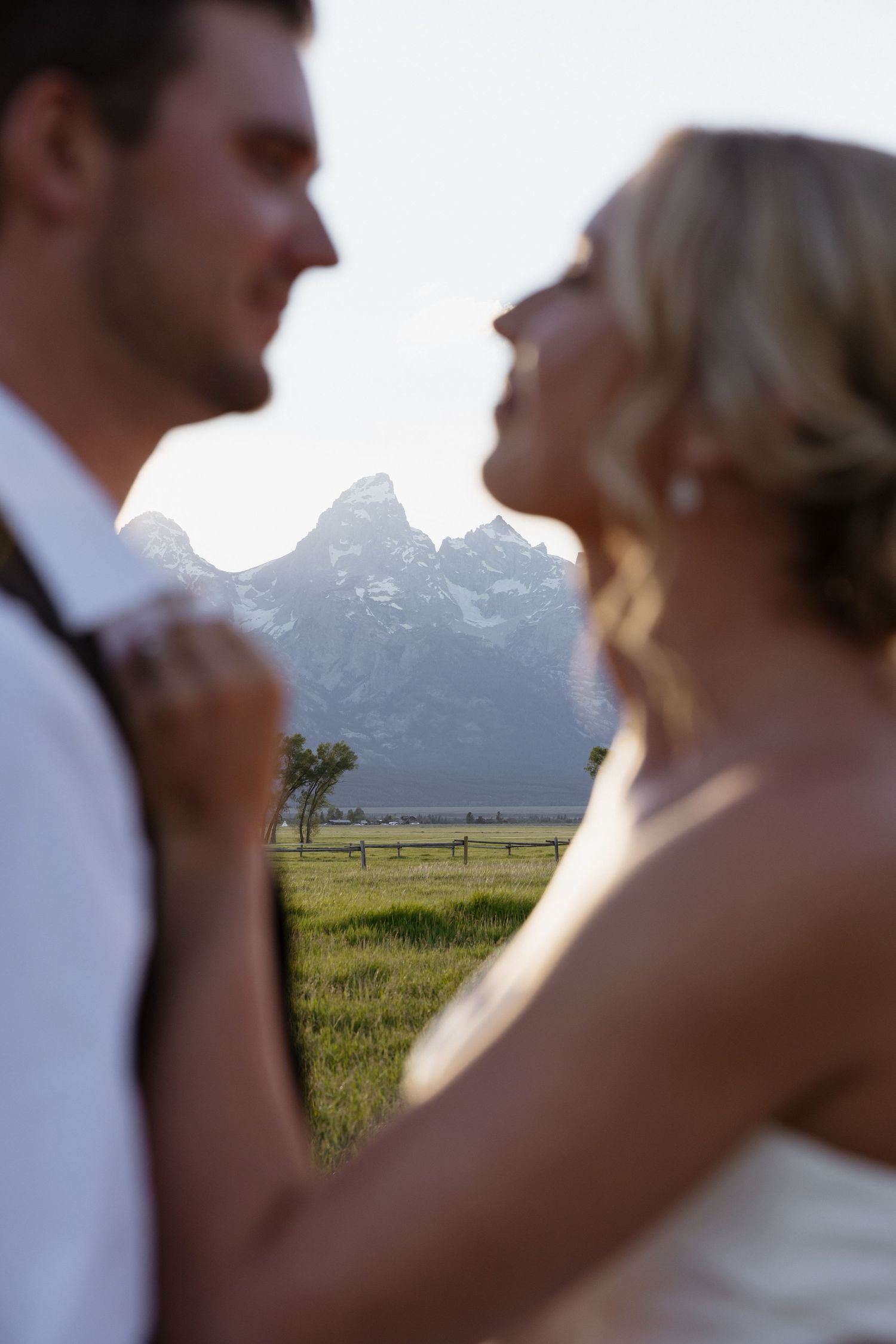 Bride and groom share an intimate moment with Grand Teton mountains in the background during their outdoor wedding.