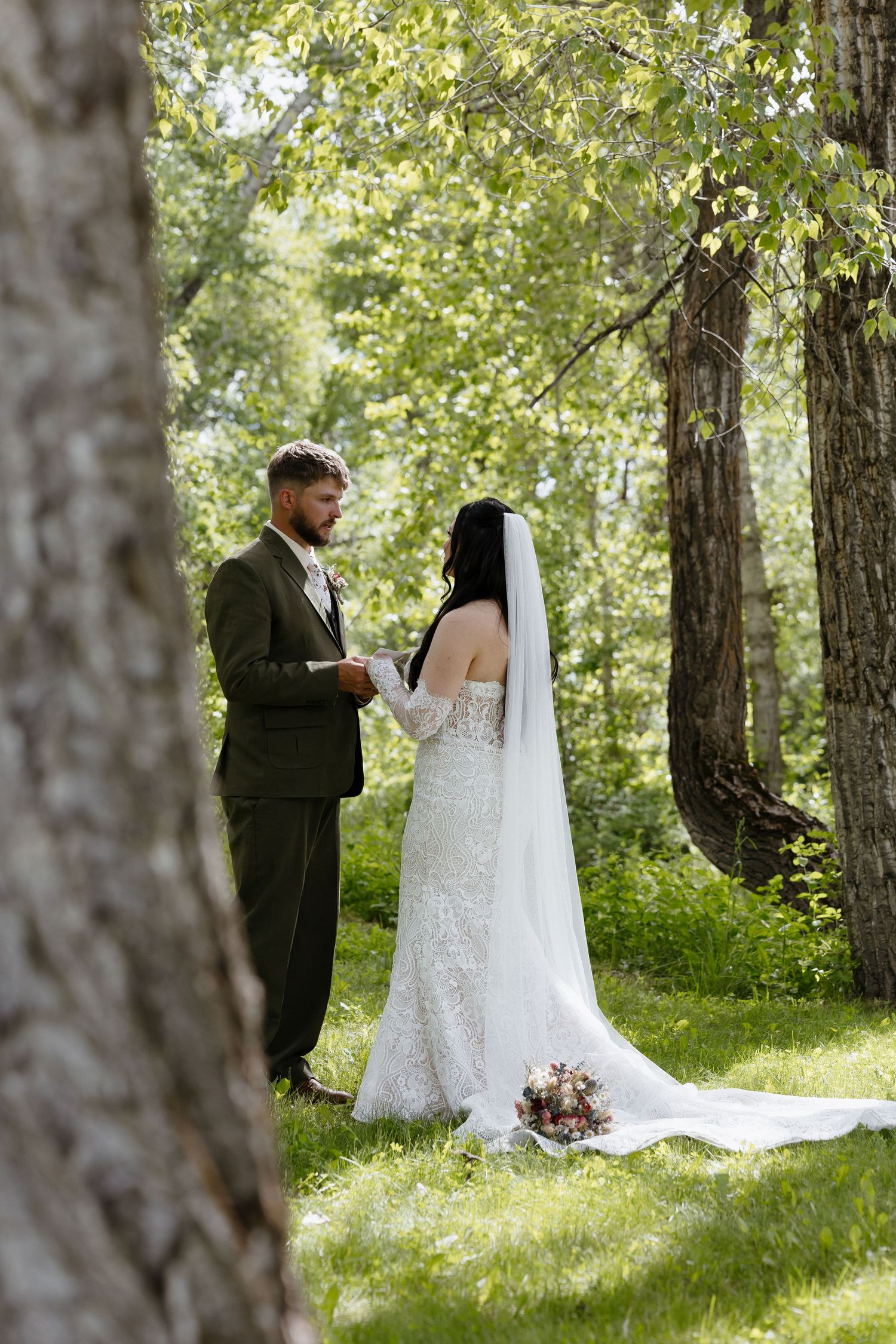 Bride and groom exchange vows in sunlit forest clearing during intimate ceremony.