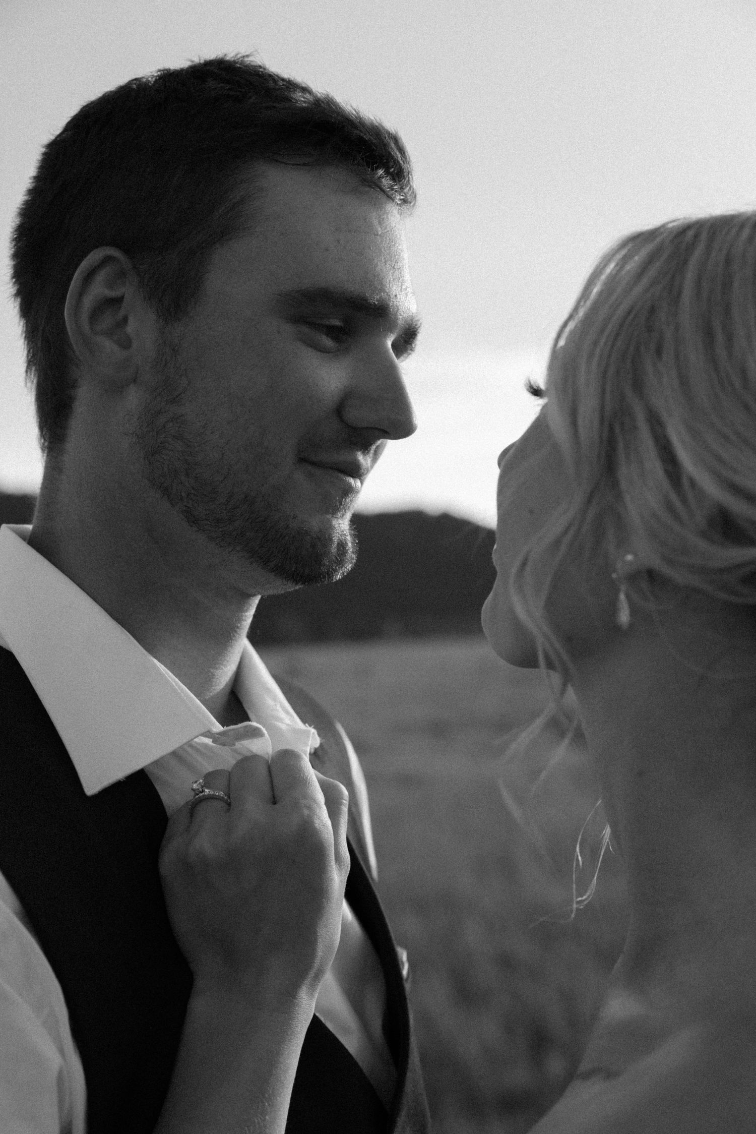 Intimate black and white portrait of smiling groom and bride facing each other in romantic moment.