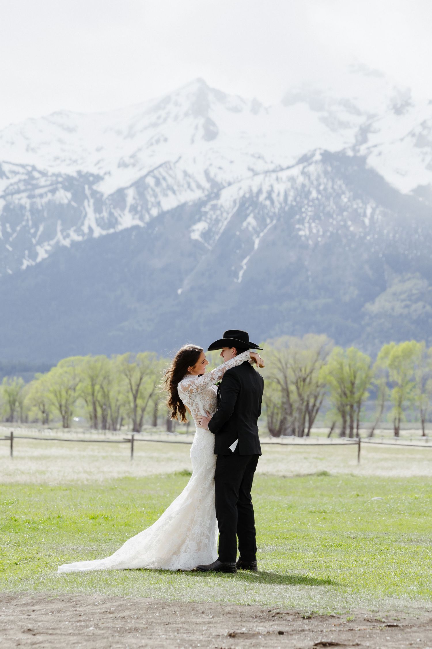 Bride and groom share romantic moment in front of snow-capped Grand Teton mountains on their wedding day.