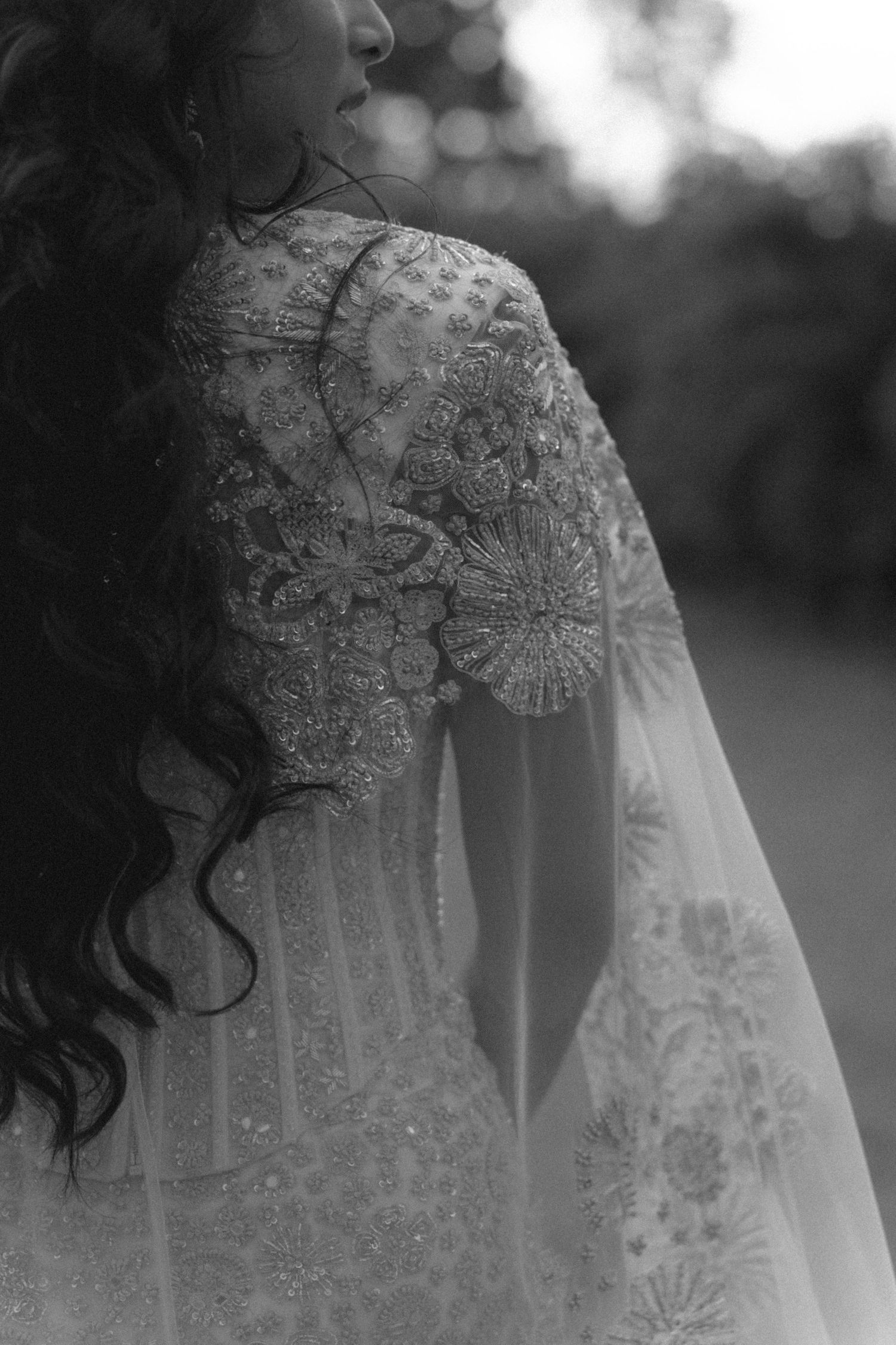 Close-up black and white photo of intricate beaded embroidery on bridal wedding gown sleeve.