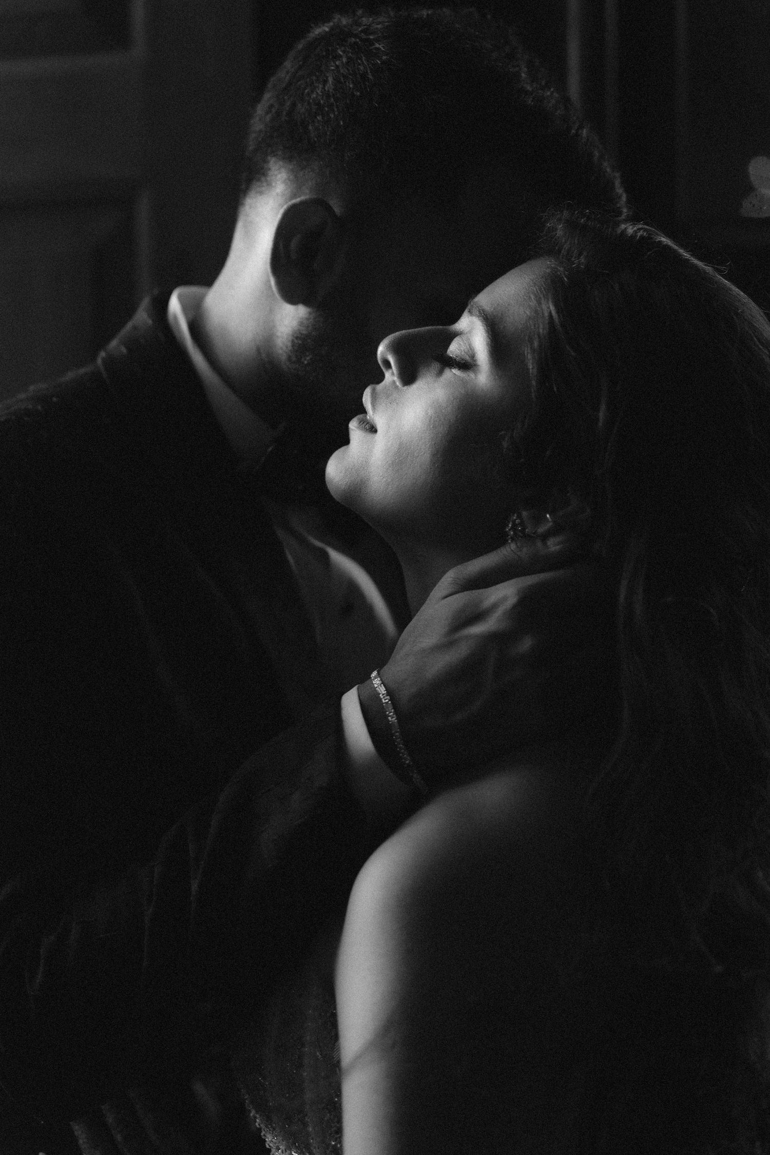Black and white romantic couple portrait with man tenderly holding womans face as they share an intimate moment.