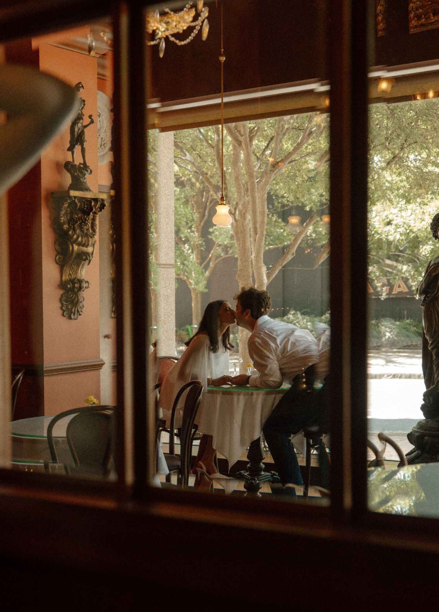 A romantic couple shares an intimate moment at a candlelit table in an elegant restaurant courtyard.