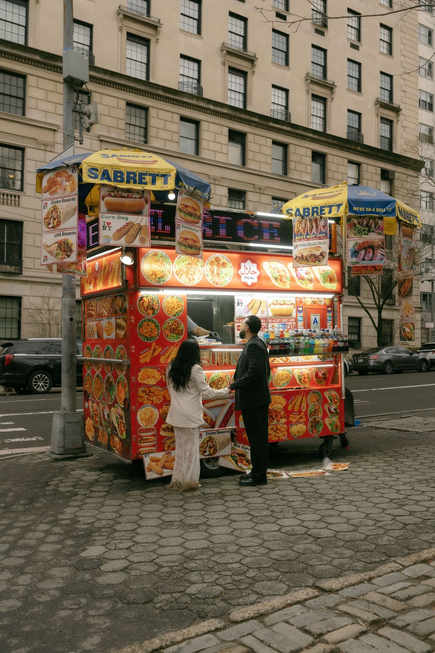 People ordering food at a colorful Sabrett hot dog street cart in New York City.
