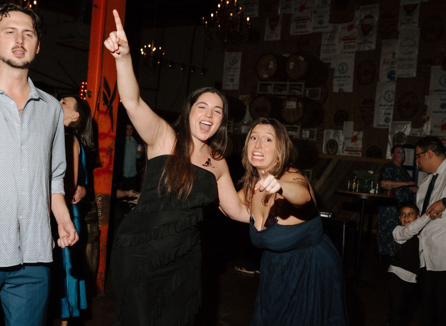 Two women dancing and celebrating at a lively indoor party event in a dimly lit venue.