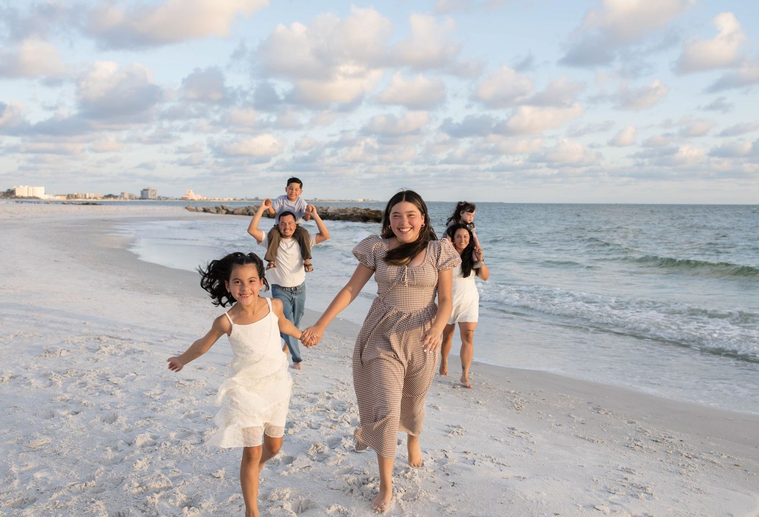 Family photos on beach in St Petersburg, Florida at sunset walking and holding hands.