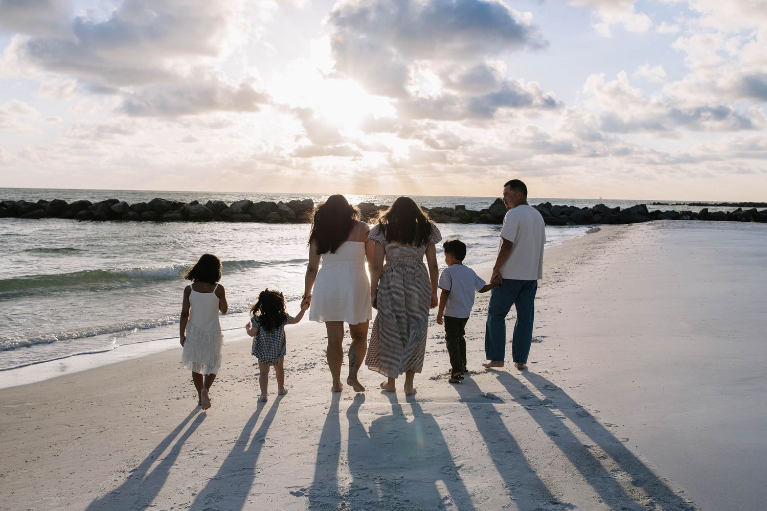 Family photos on beach in St Petersburg, Florida at sunset walking and holding hands.