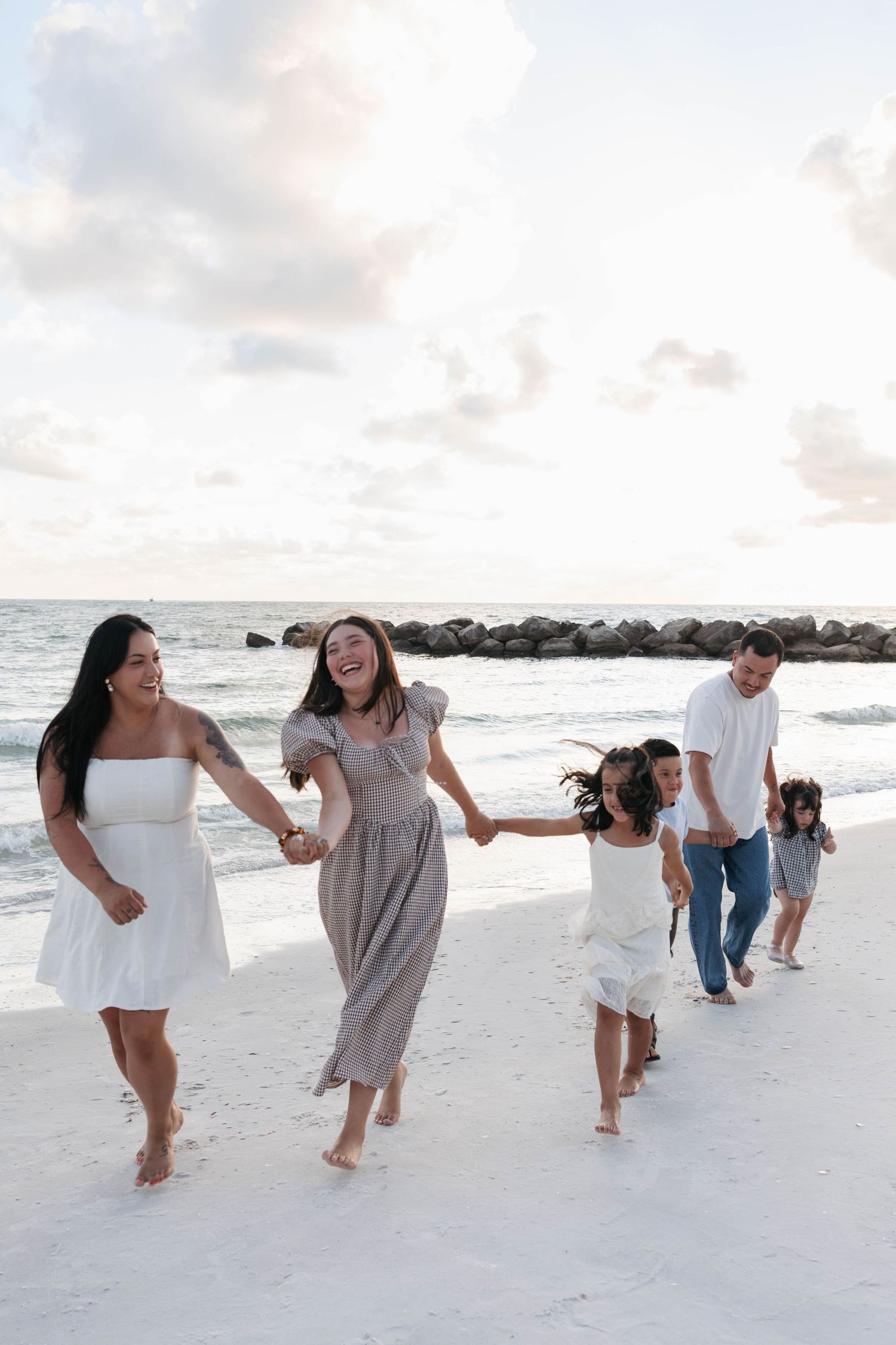 Family photos on beach in St Petersburg, Florida at sunset walking and holding hands.