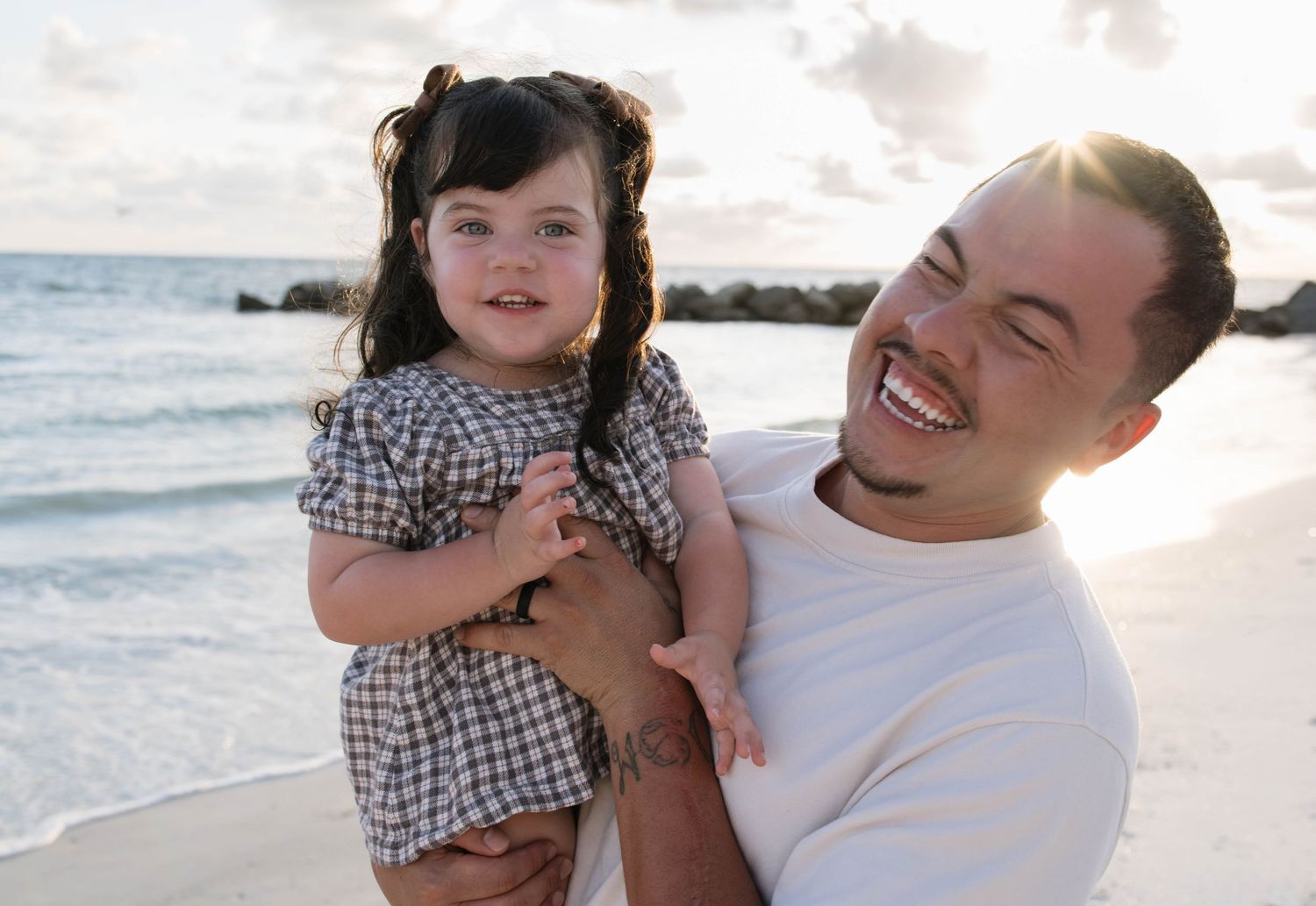 dad and daughter laughing during family photoshoot on beach in Tampa, Florida.