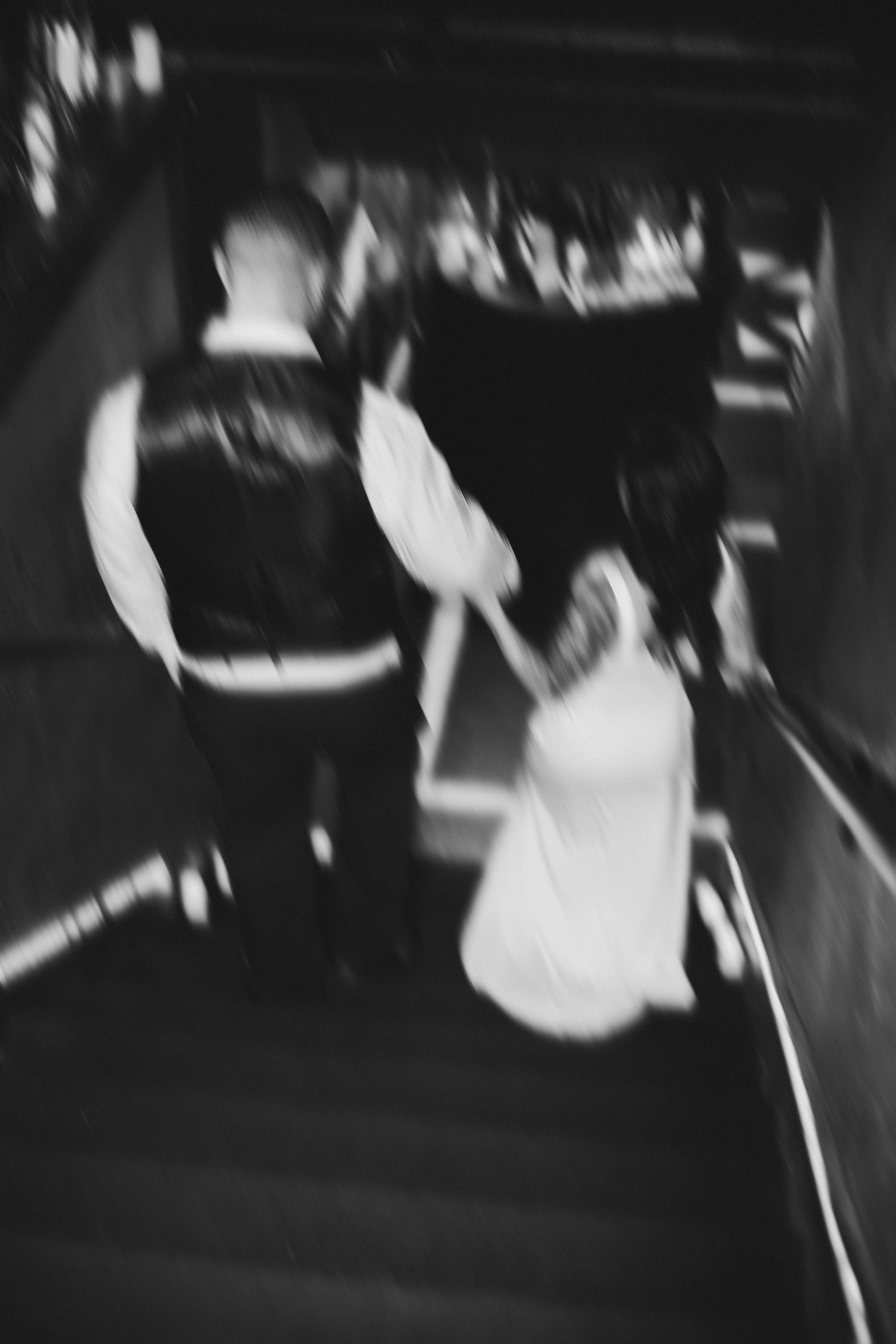 Blurry black and white photo of bride and groom walking up stairs at wedding reception.