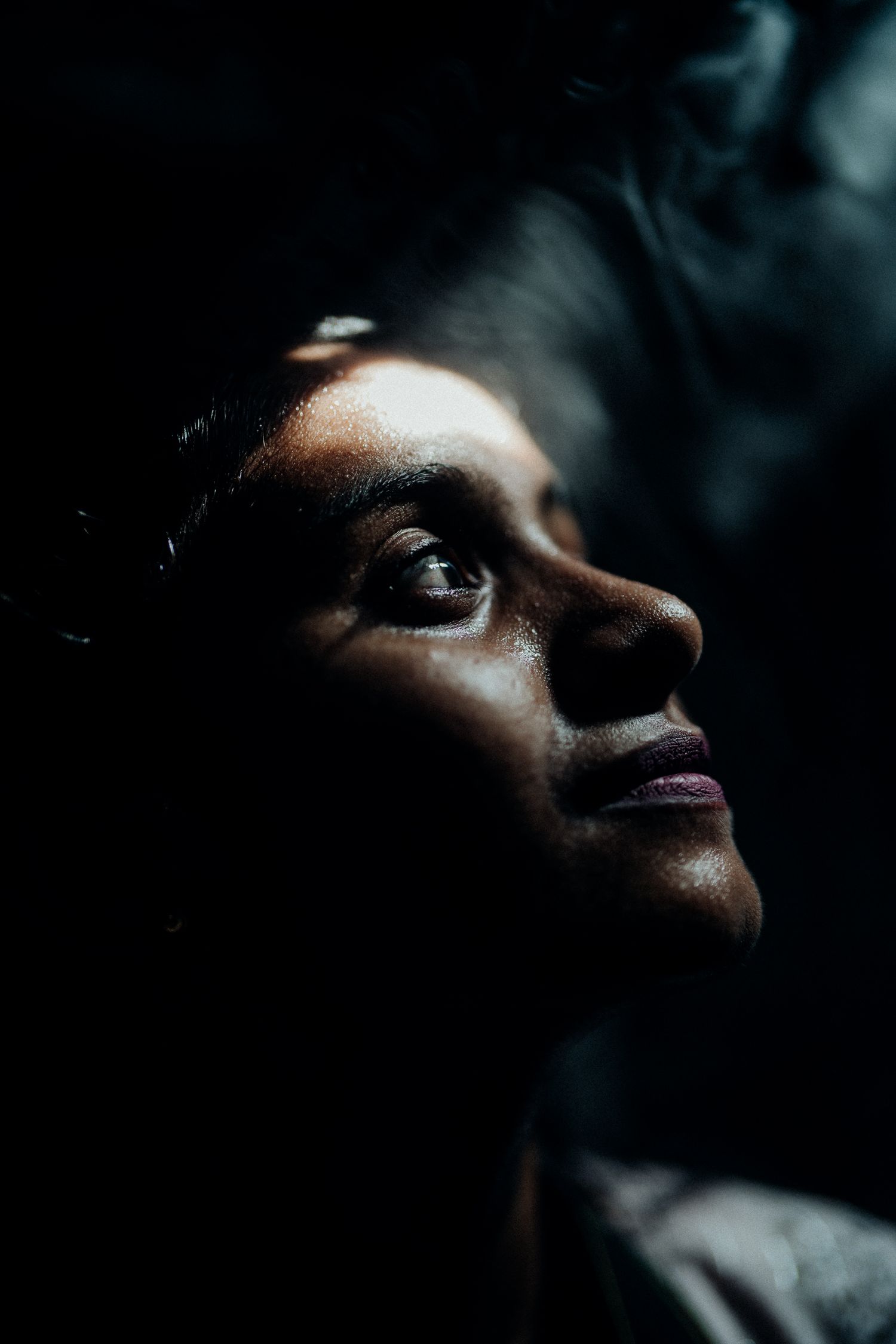 Dramatic side-lit portrait with strong contrast between light and shadow.